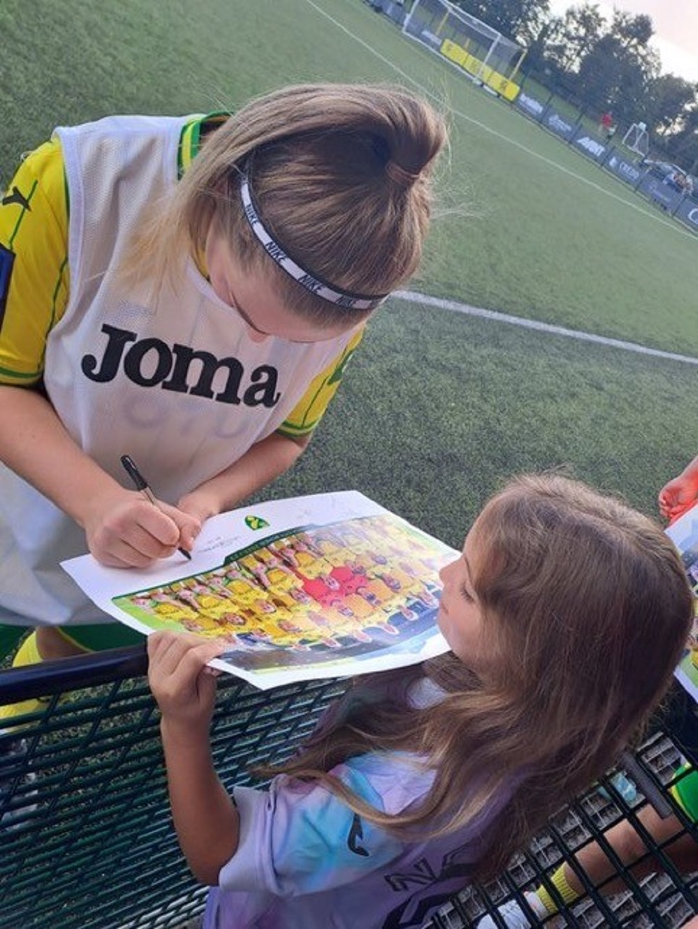 Girl having photo signed by a woman, who is wearing a headband