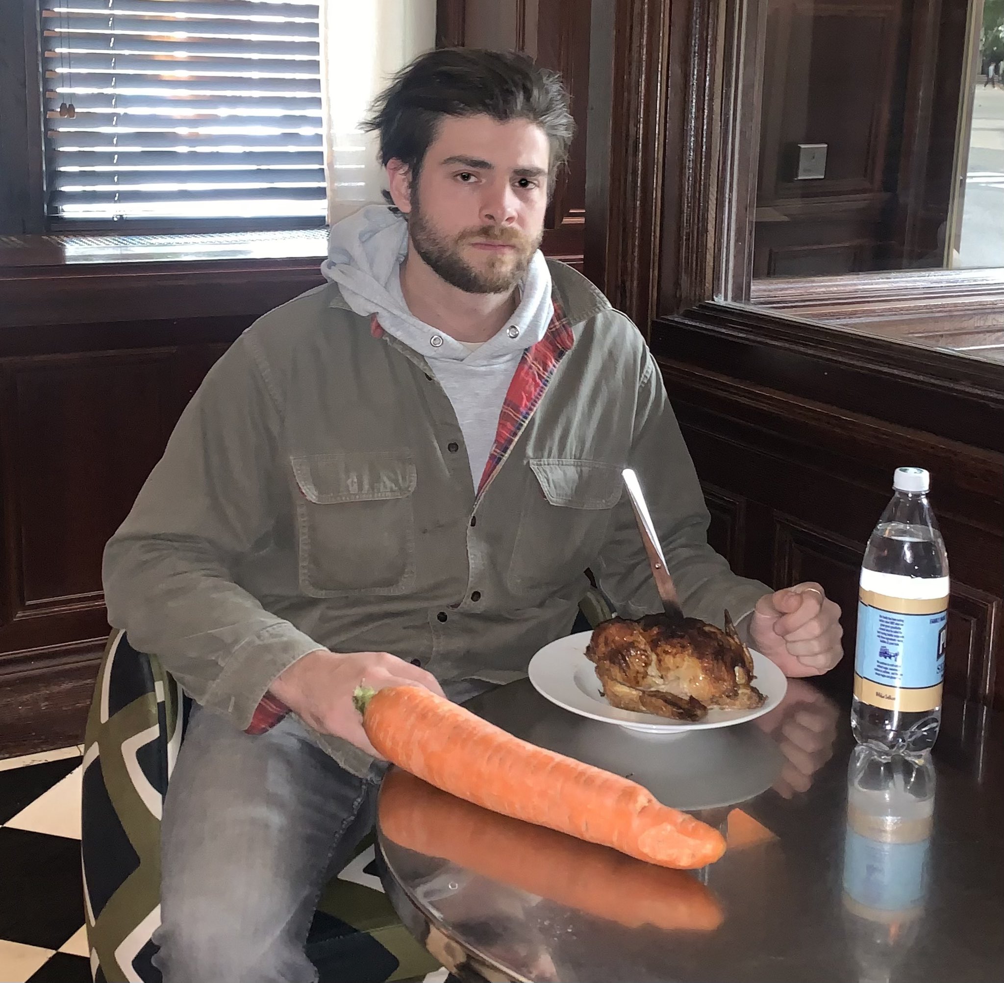 Man looking at the camera, with a carrot and bowl in front of him