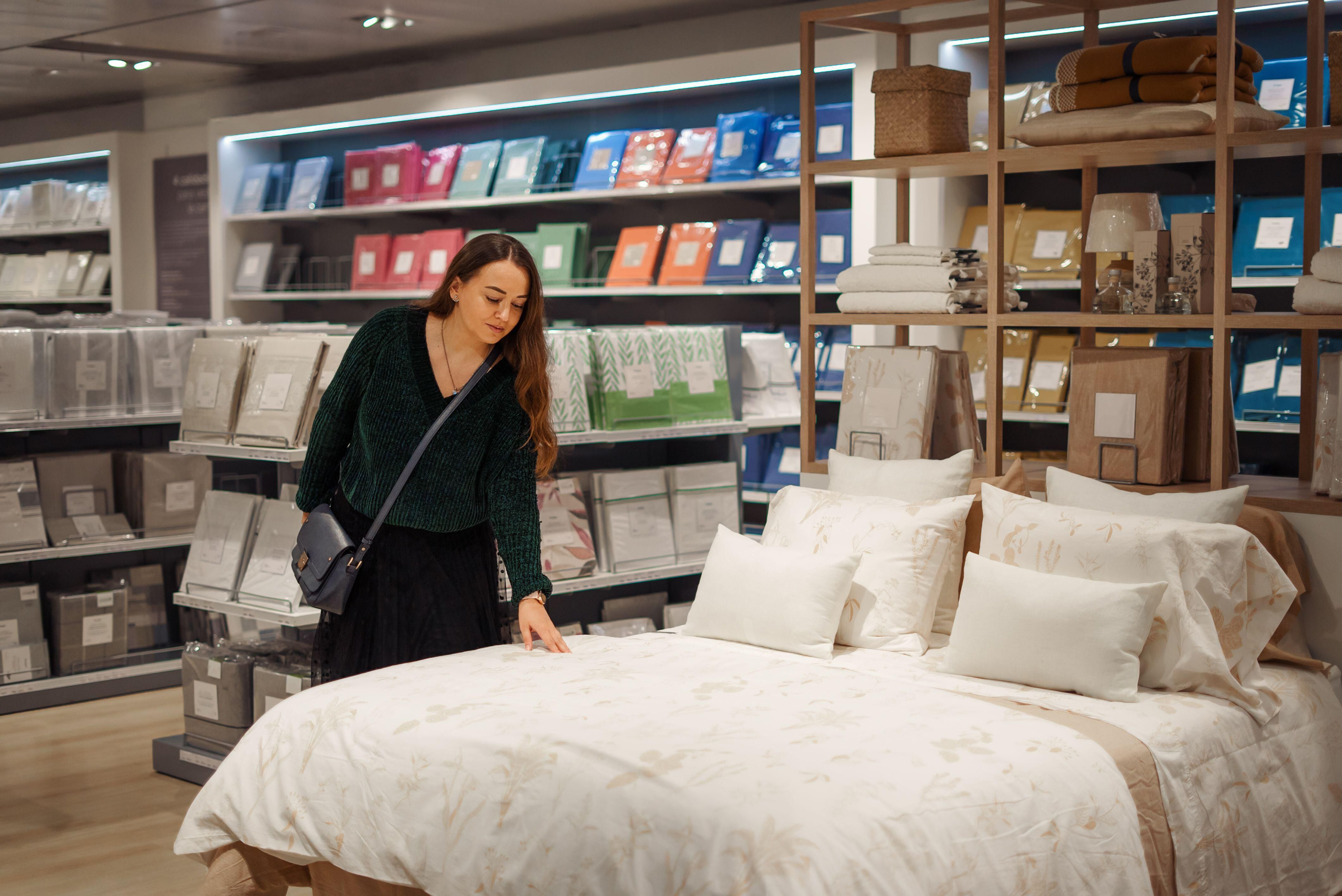 Woman gently touching bedding in department store