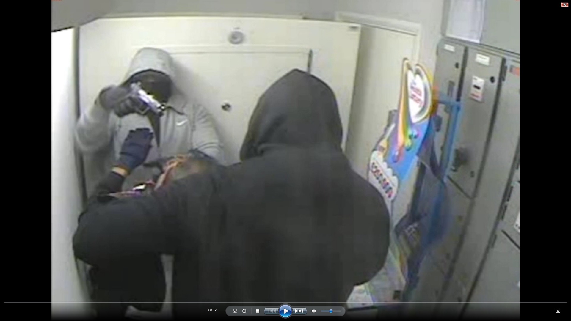 Two members of the gang brandishing a gun at a security guard during one of the robberies.