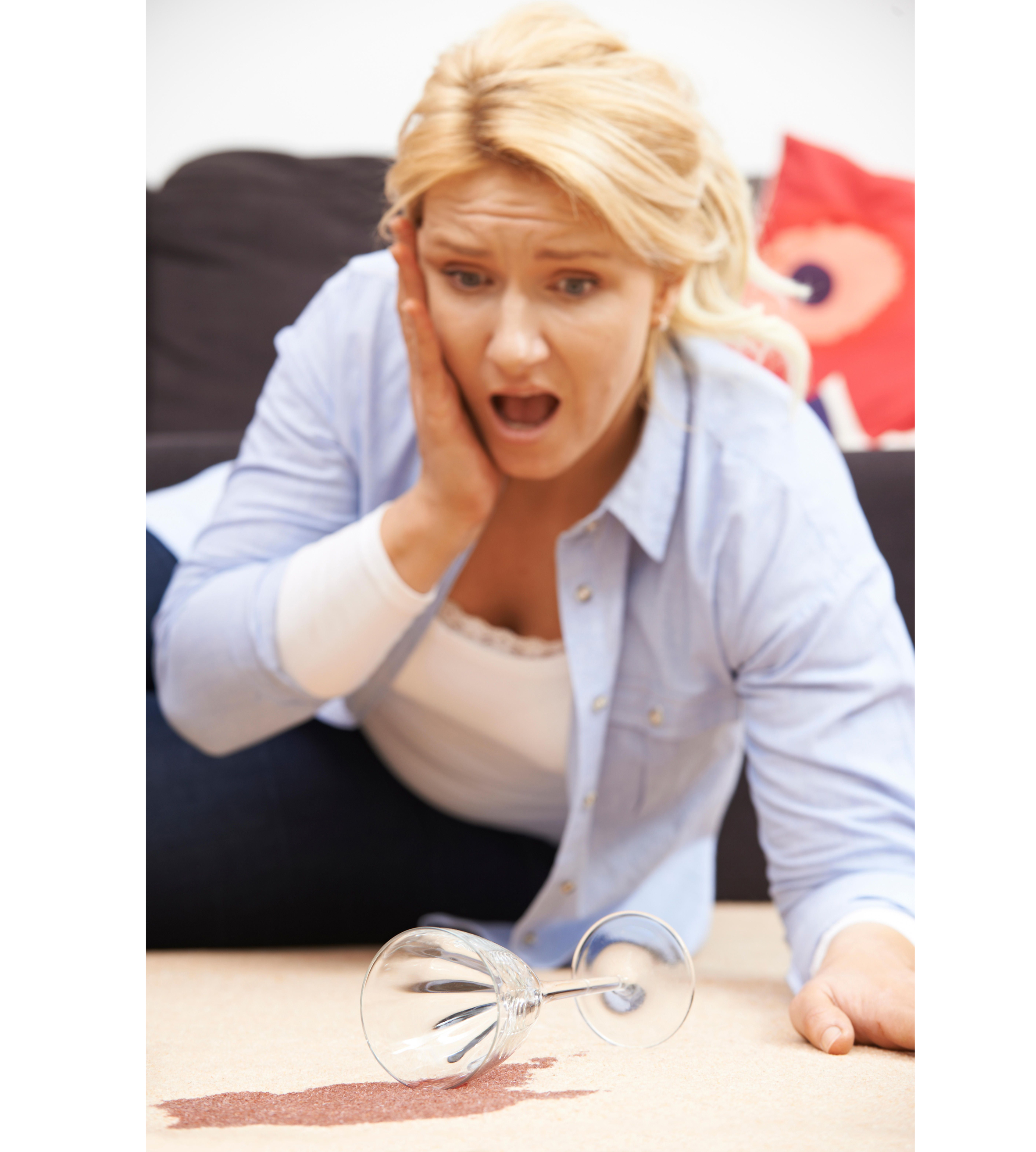 Woman accidentally spilling red wine on carpet