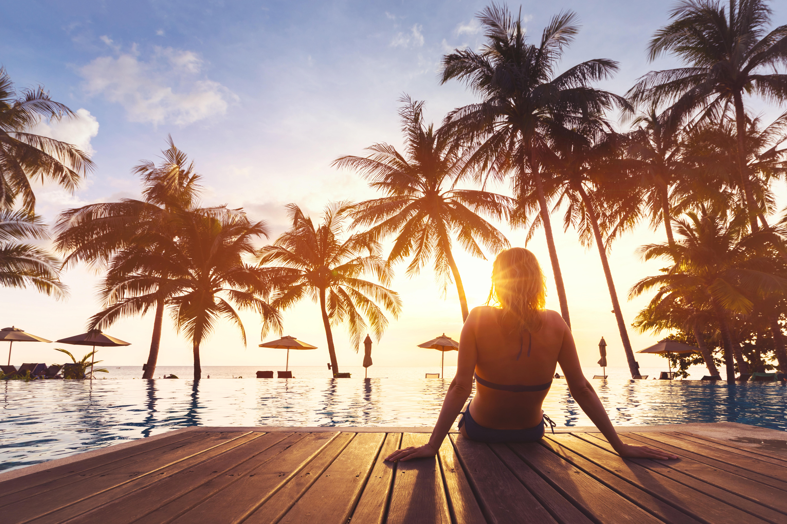 Woman sitting by pool at sunset