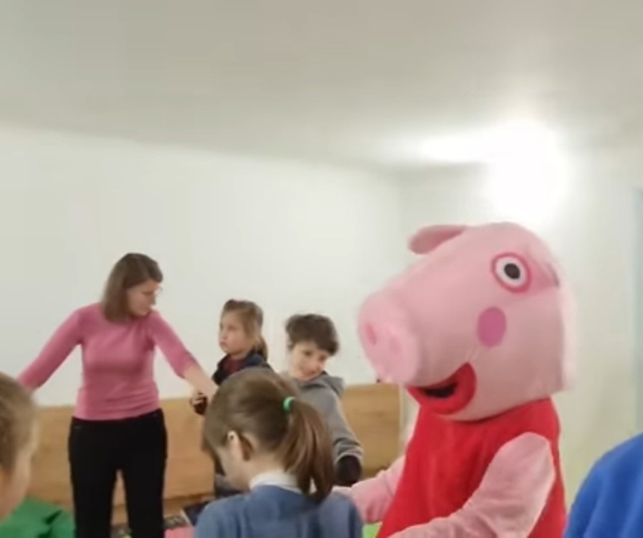Woman dressed as Peppa Pig in a room with children