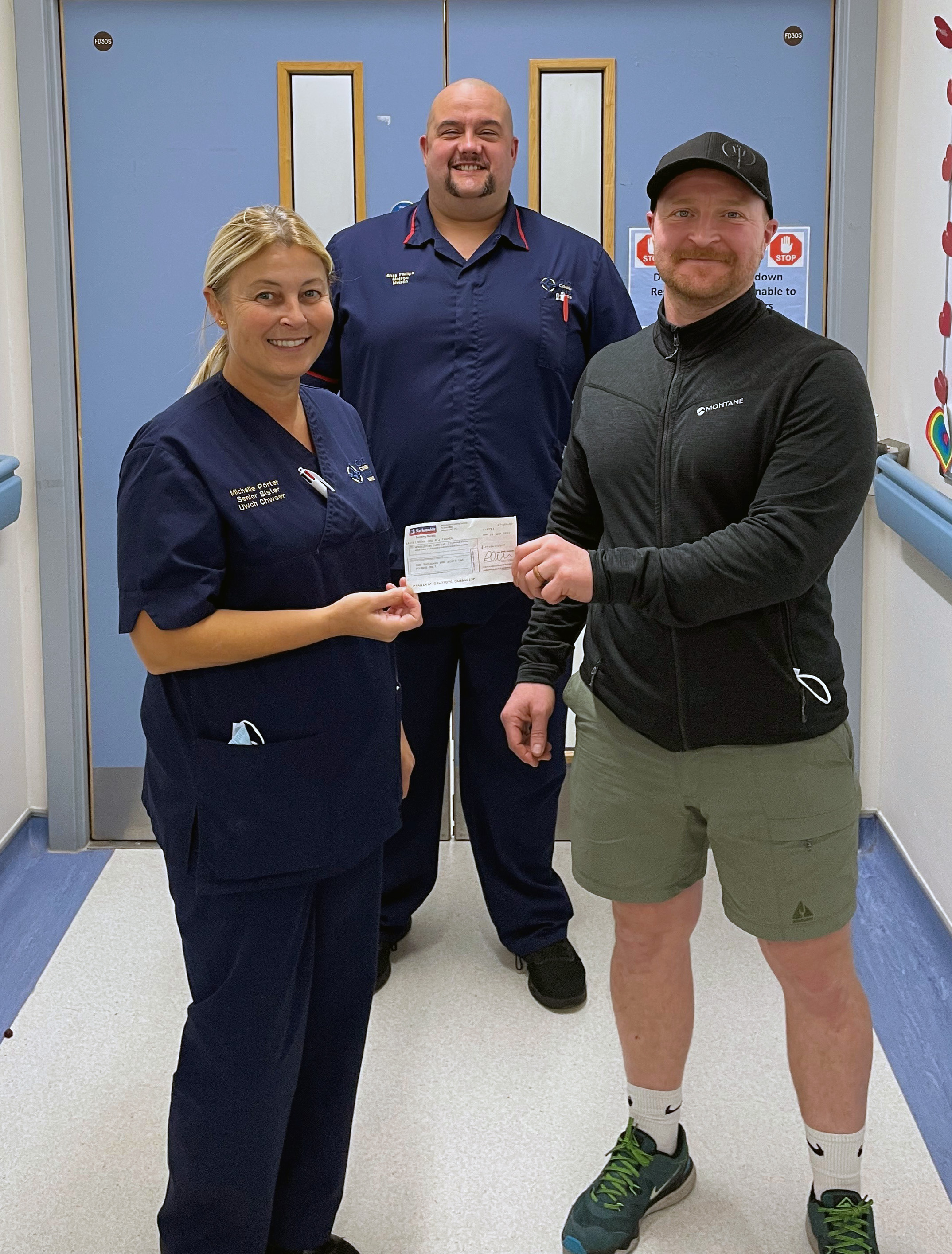 Mr Jones, who underwent heart surgery at the Morriston Hospital in Swansea, hands over a cheque for £1,100 he raised climbing North Africa's tallest mountain (Swansea Bay University Health Board/PA)