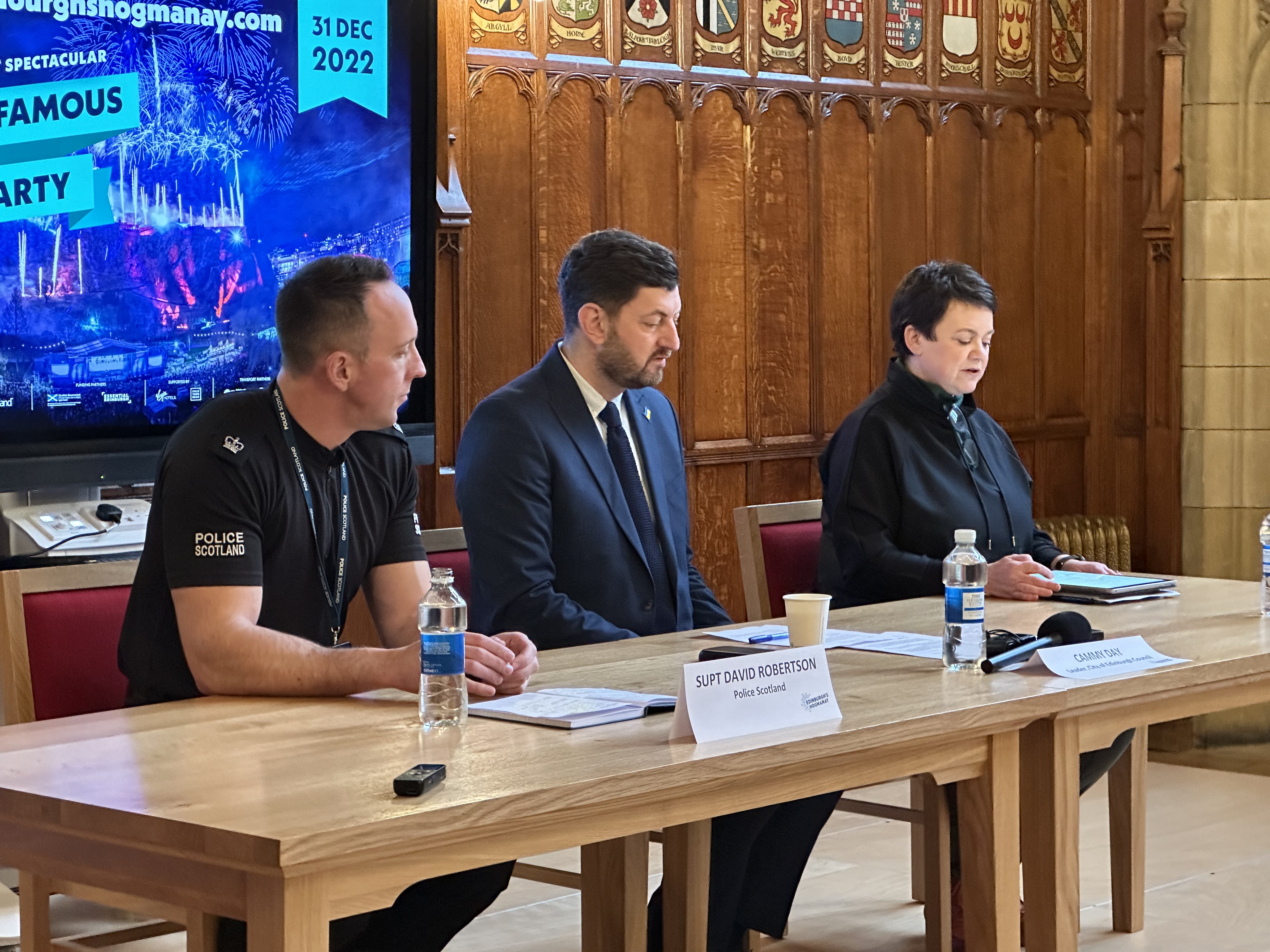 three people sat at a table giving a press conference 