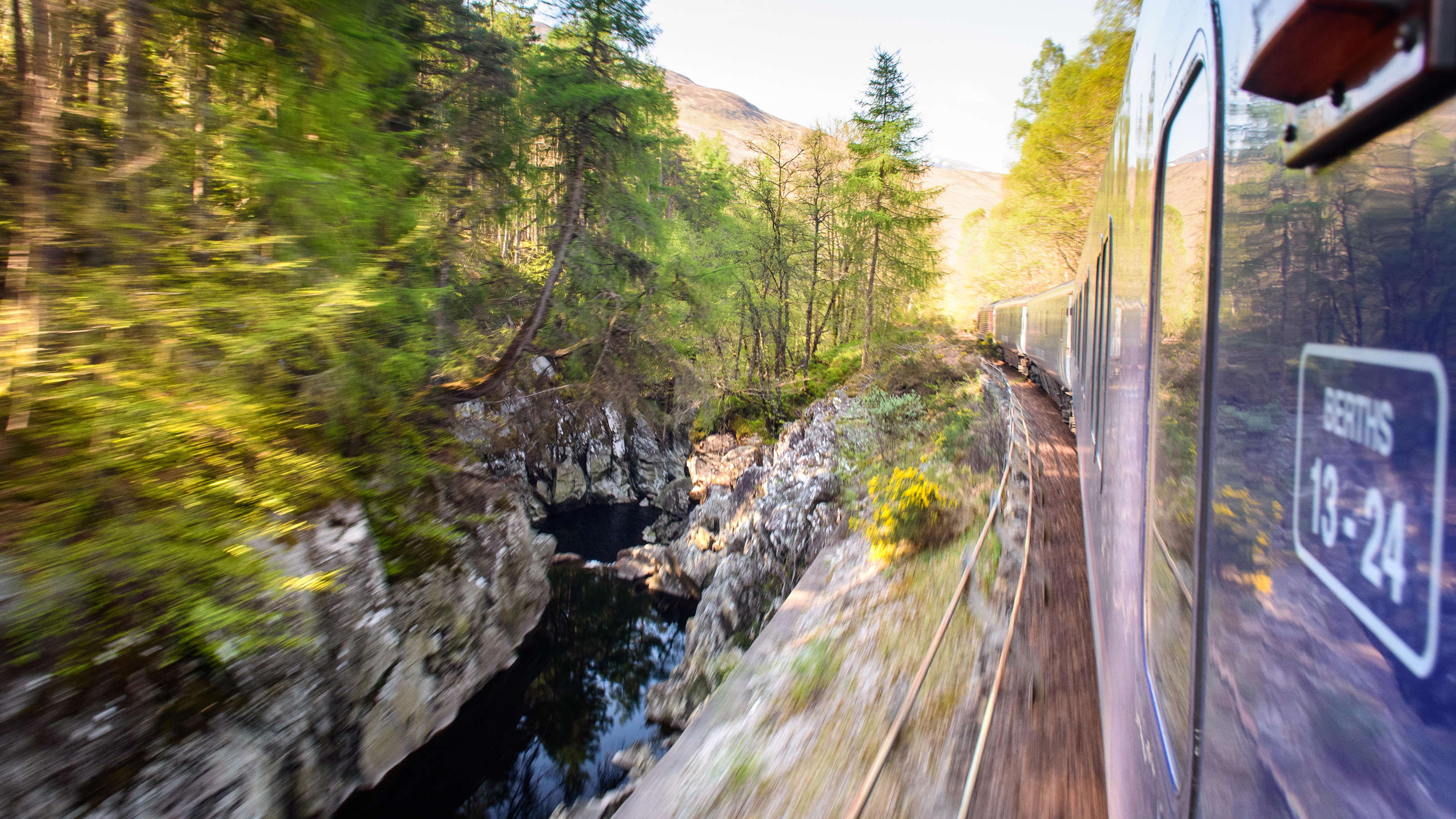 The Caledonian Sleeper train runs alongside the waters of the Monessie Gorge on the scenic West Highland Line