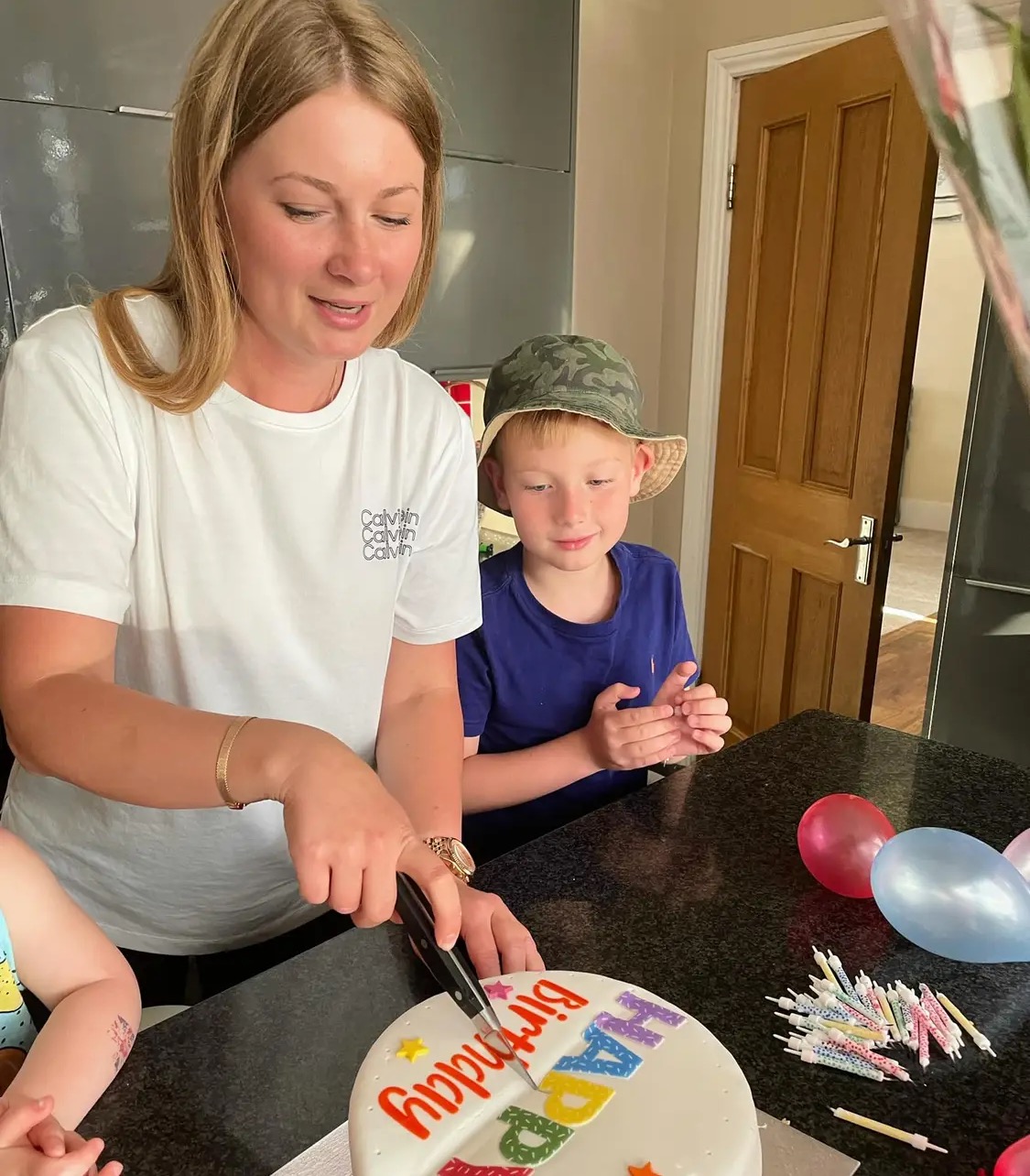 Woman cutting a cake next to a boy looking at the cake