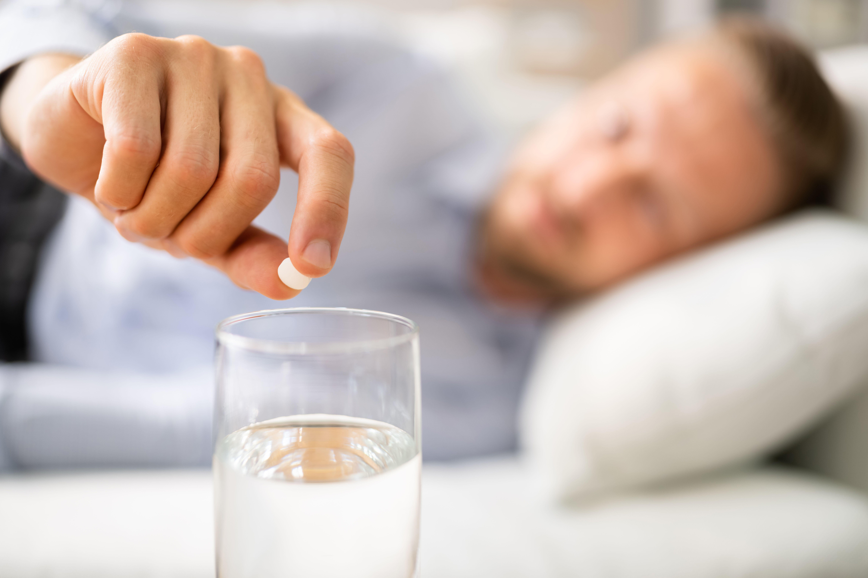 man with hangover putting painkiller into water