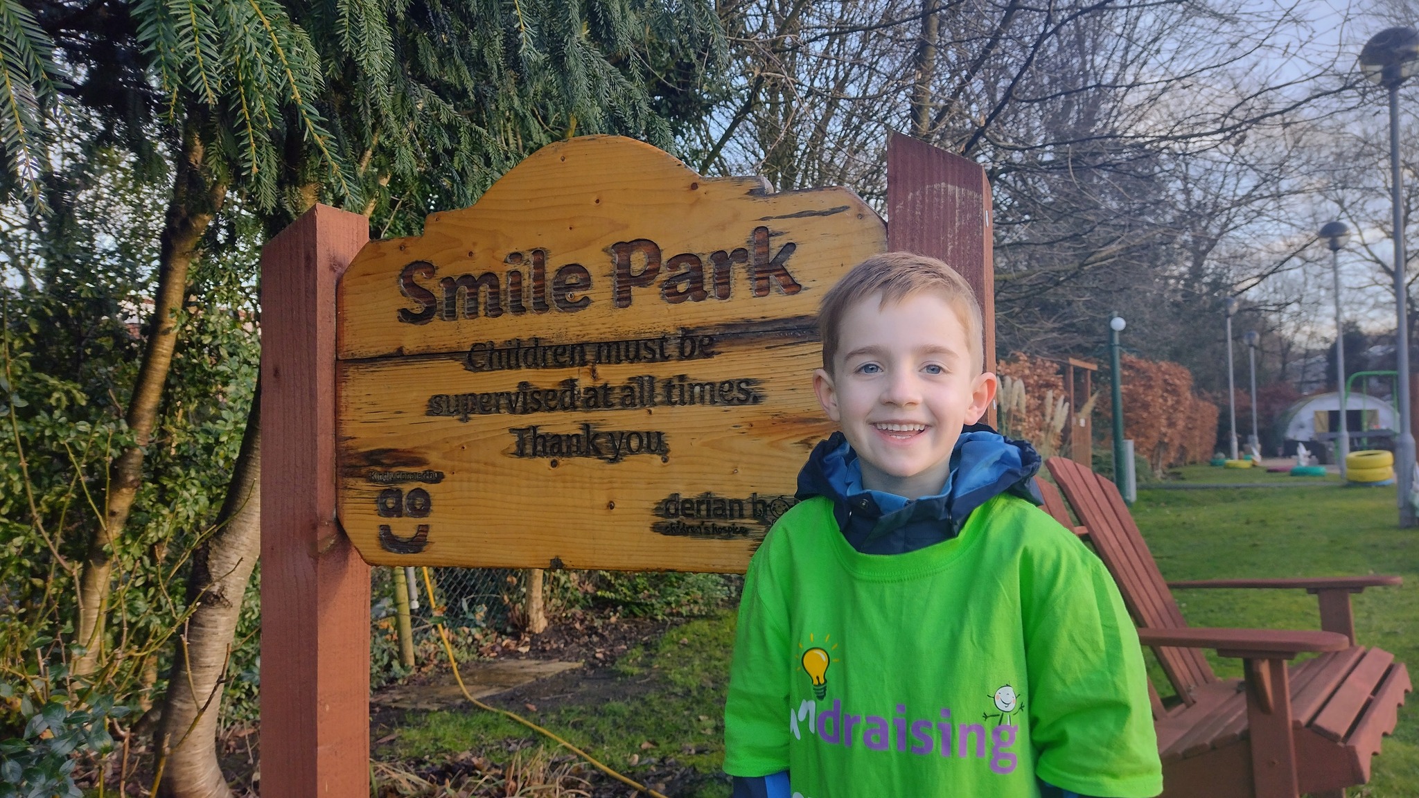 Boy standing in front of a sign and smiling 