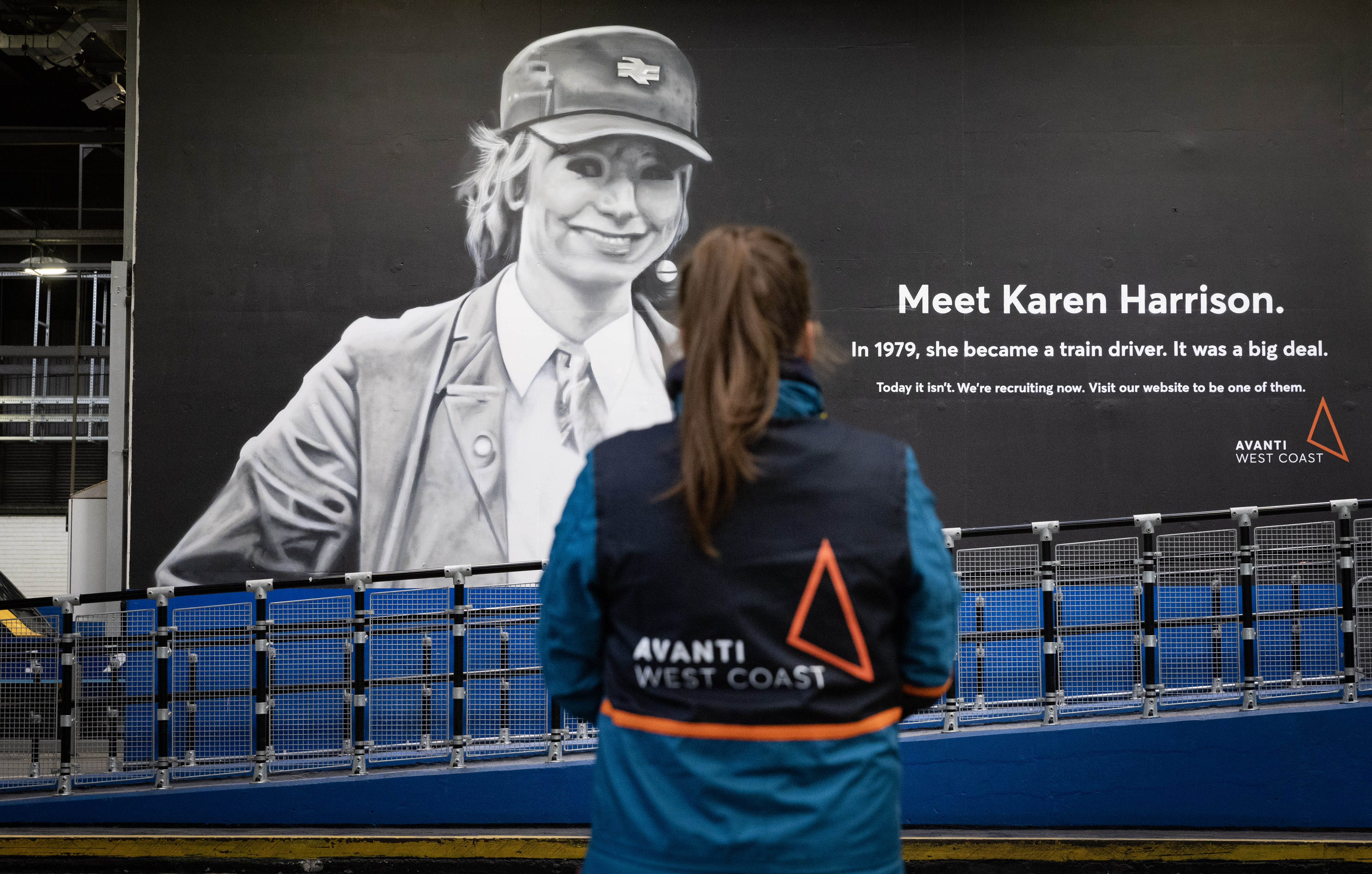 An Avanti West Coast crew member looks at a mural of Karen Harrison