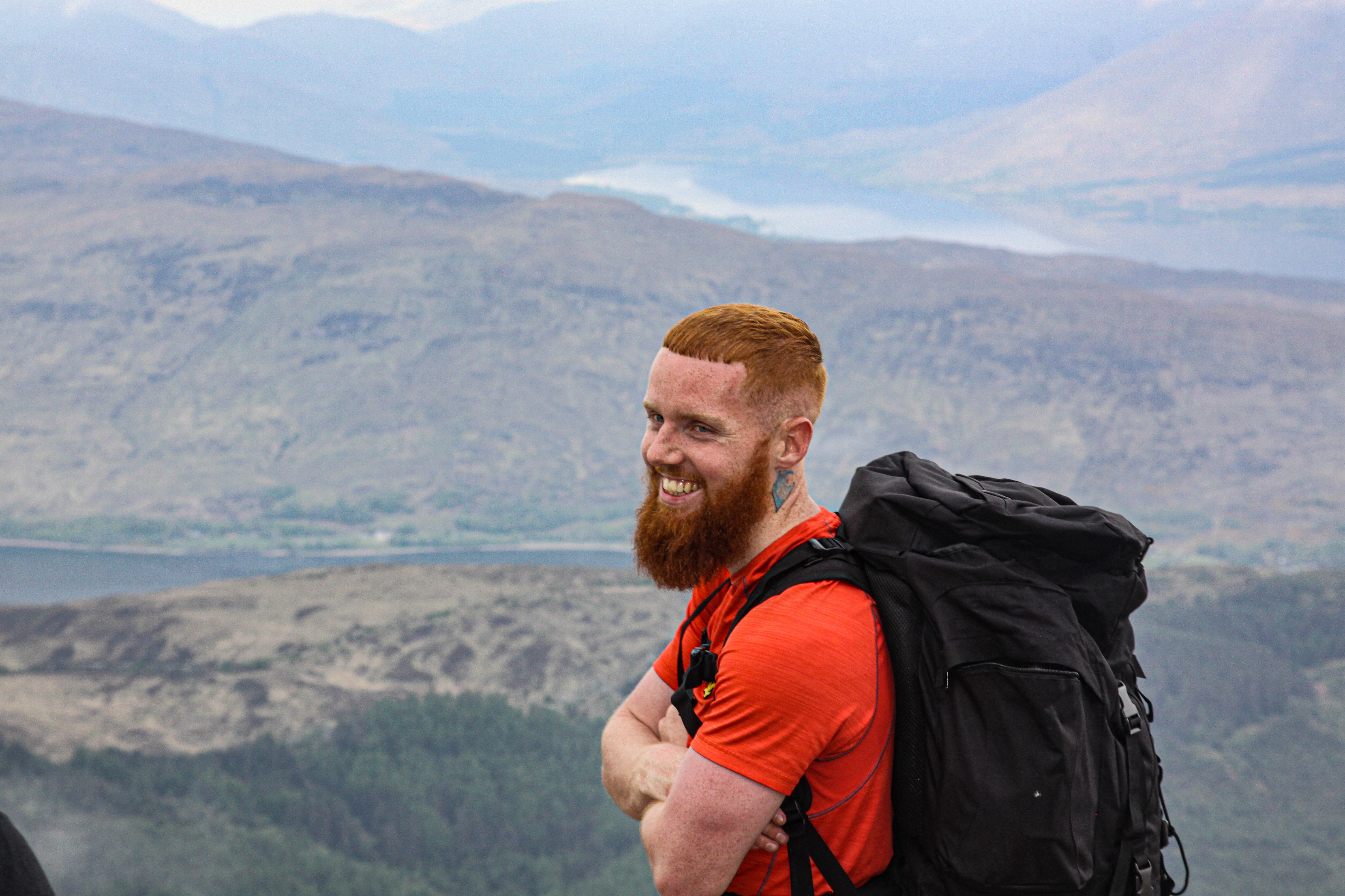 Man wearing an orange top and rucksack and smiling