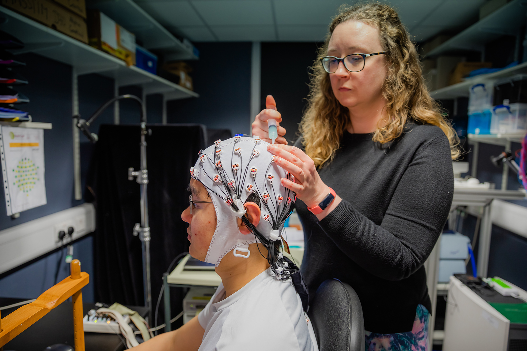 Lead author Dr Elizabeth Michael tweaks the electroencephalography cap, as demonstrated by Adaptive Brain Lab researcher Ye Gu. (Cambridge University/ PA)