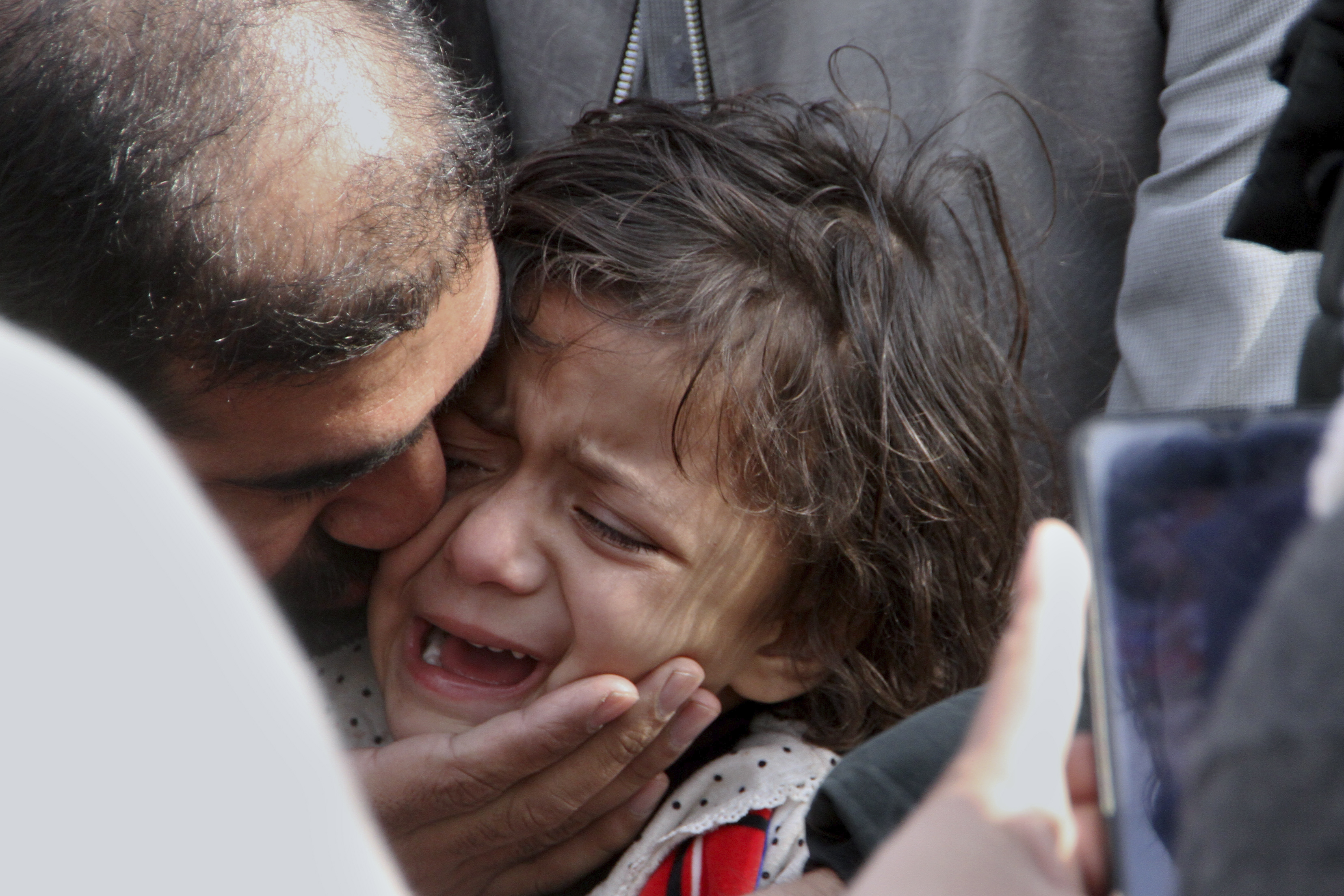 A man comforts a girl who lost her father in Monday's suicide bombing