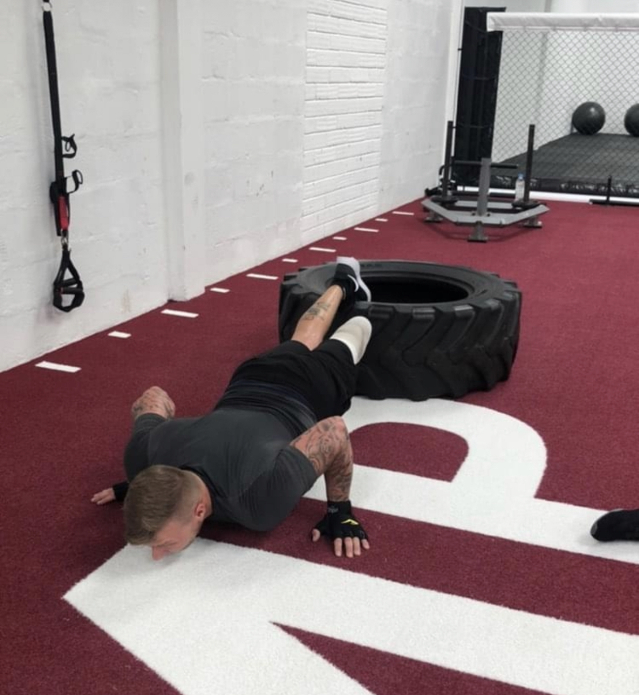 Man doing a push-up, with a tyre near his foot
