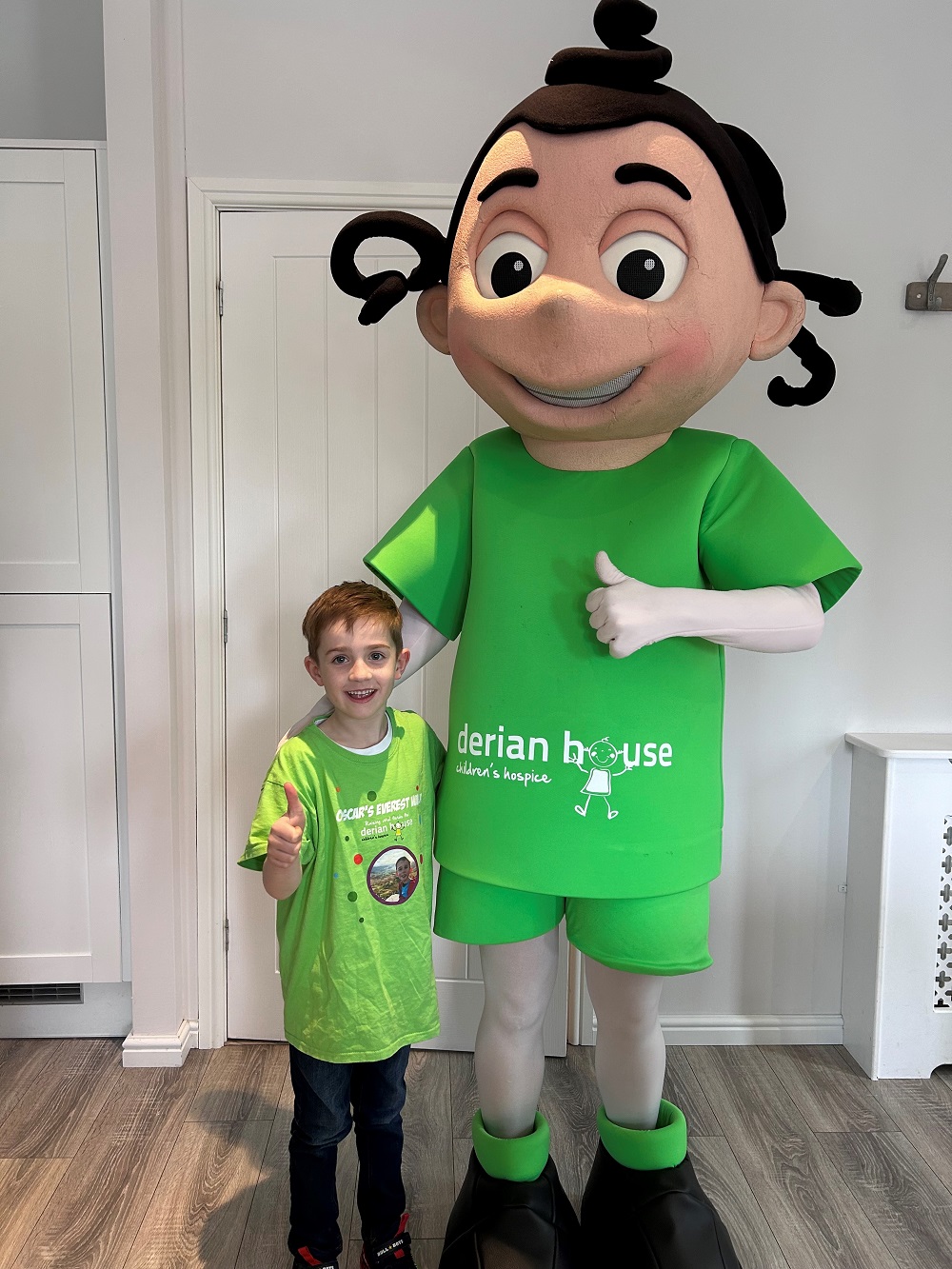 Little boy standing next to man with costume on, with both their thumbs up