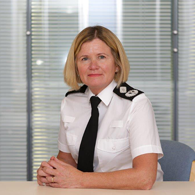 Deputy Chief Constable Maggie Blyth wearing uniform sitting at a desk.