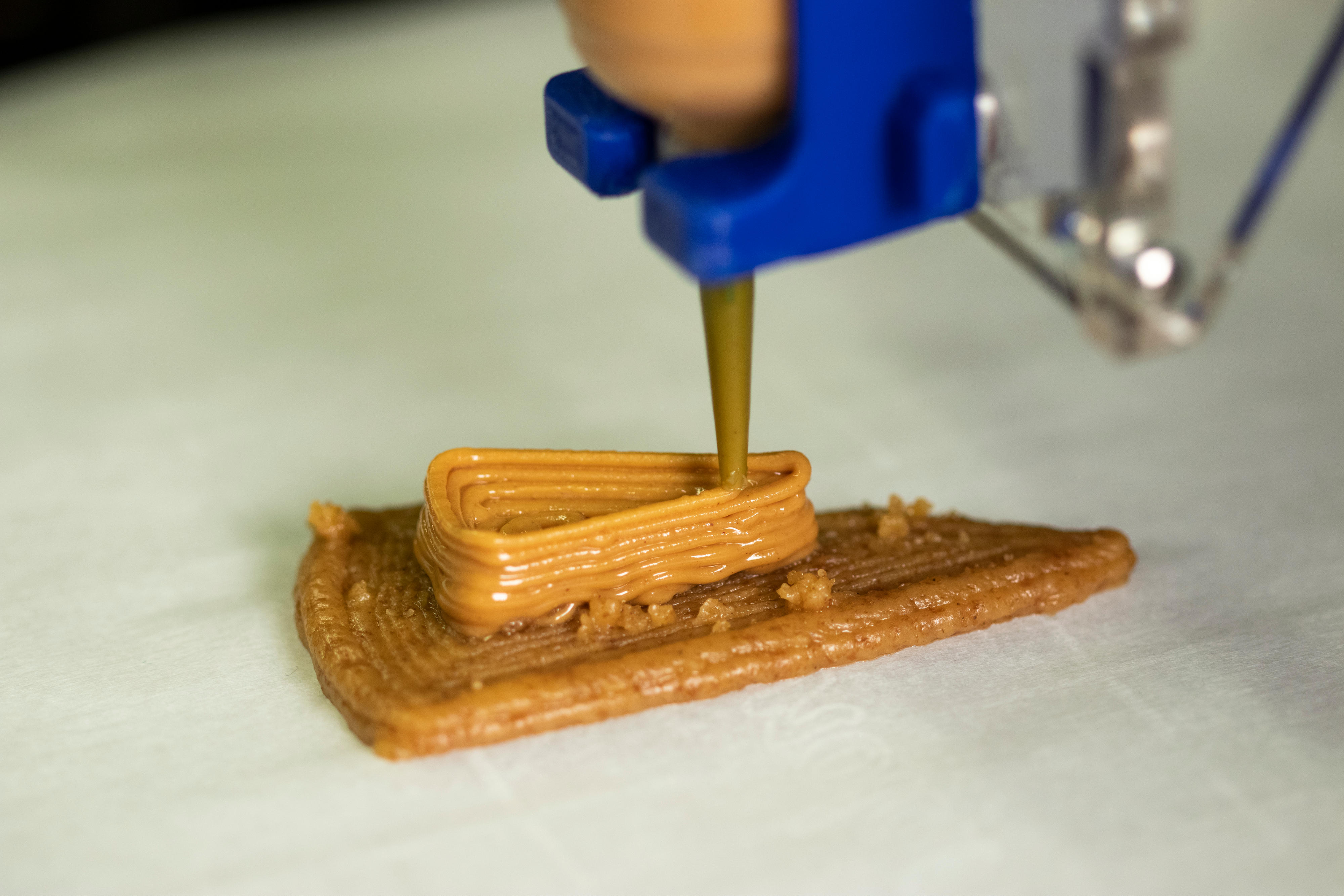 Peanut butter being deposited onto a layer of graham cracker paste 