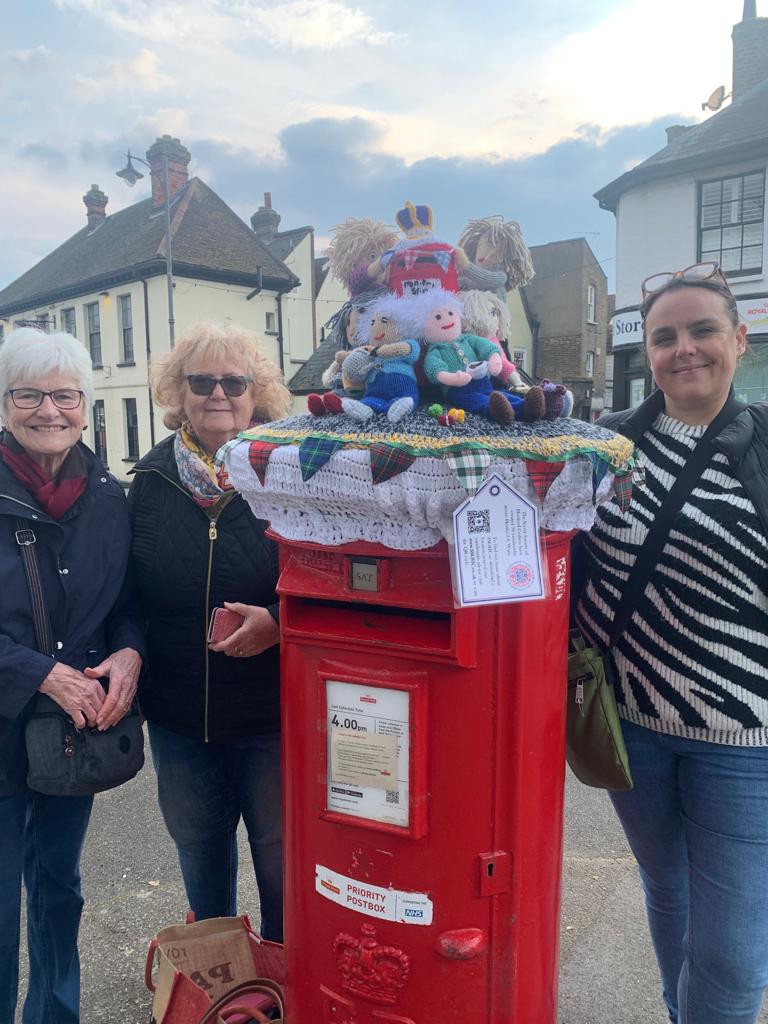 Three women standing next to a postbox