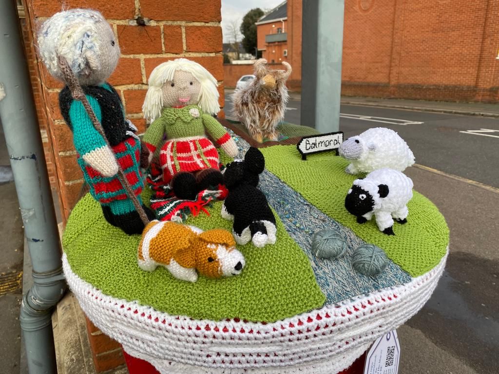 People and animals on top of postbox in a crochet form