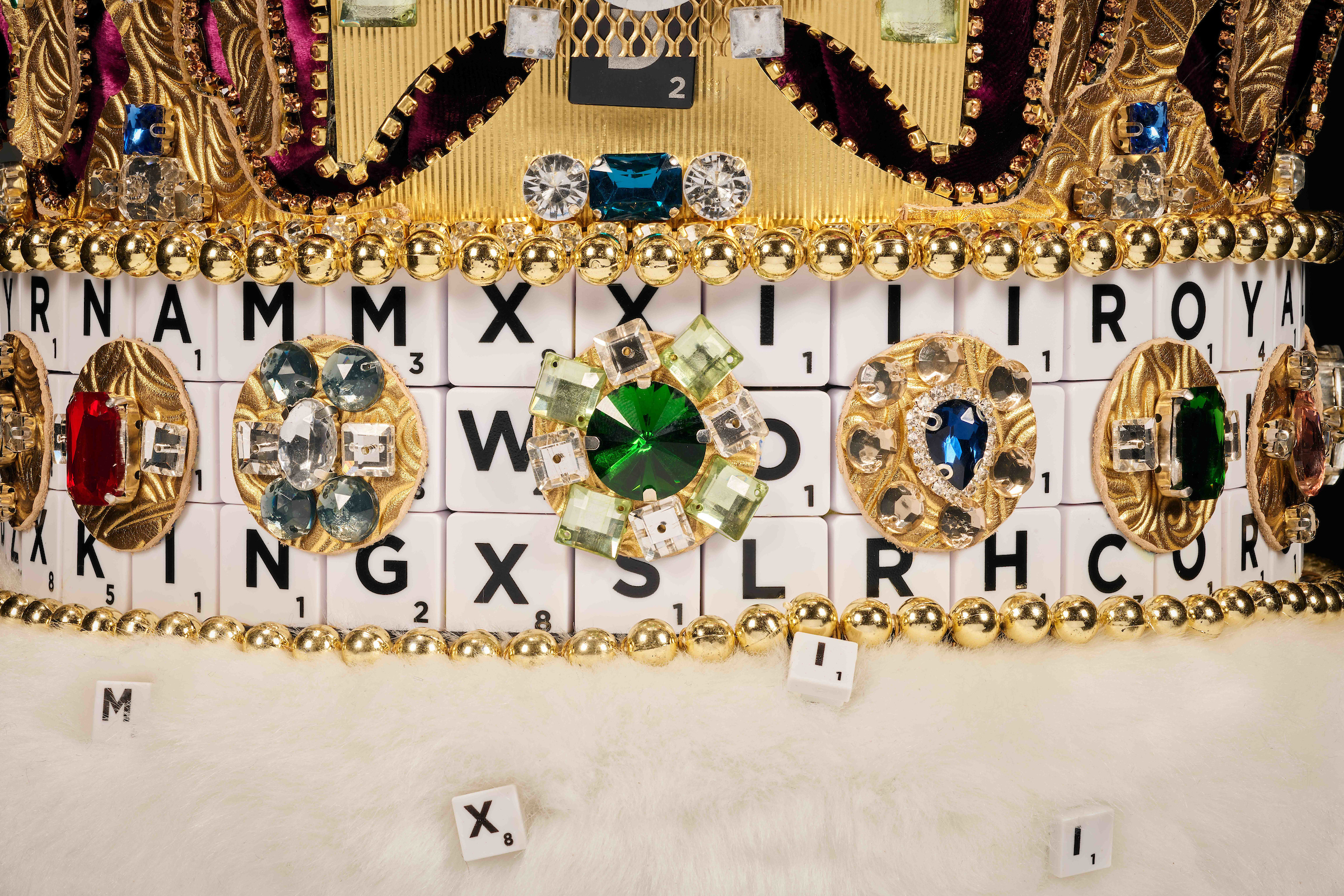 Close up pf Scrabble letters on the rim of a golden crown 