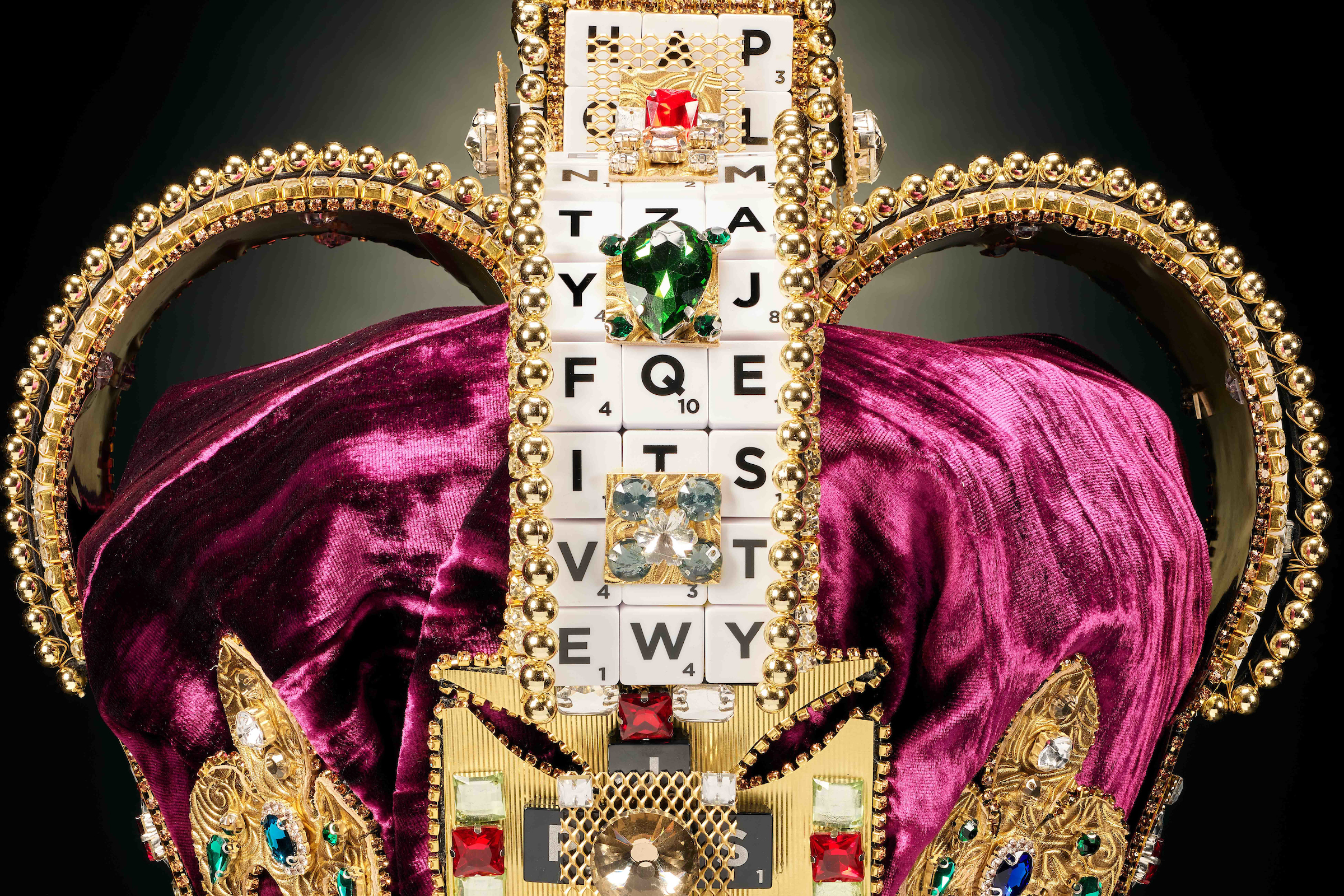 Top of a crown, which has Scrabble pieces and jewels on it 