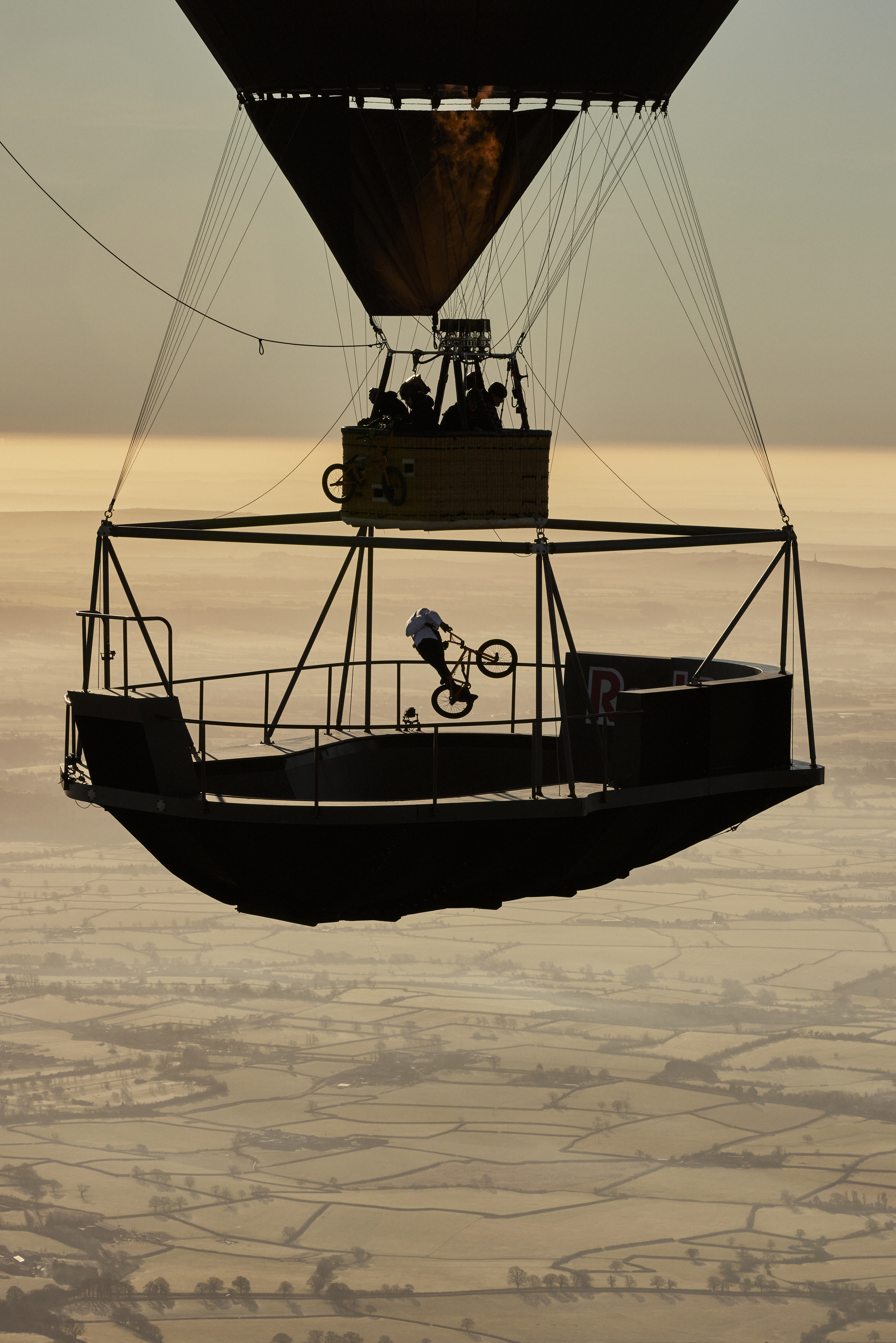 A BMX Athlete performs rides around a floating skatepark suspended 2,100 feet in the air by a large hot air balloon.