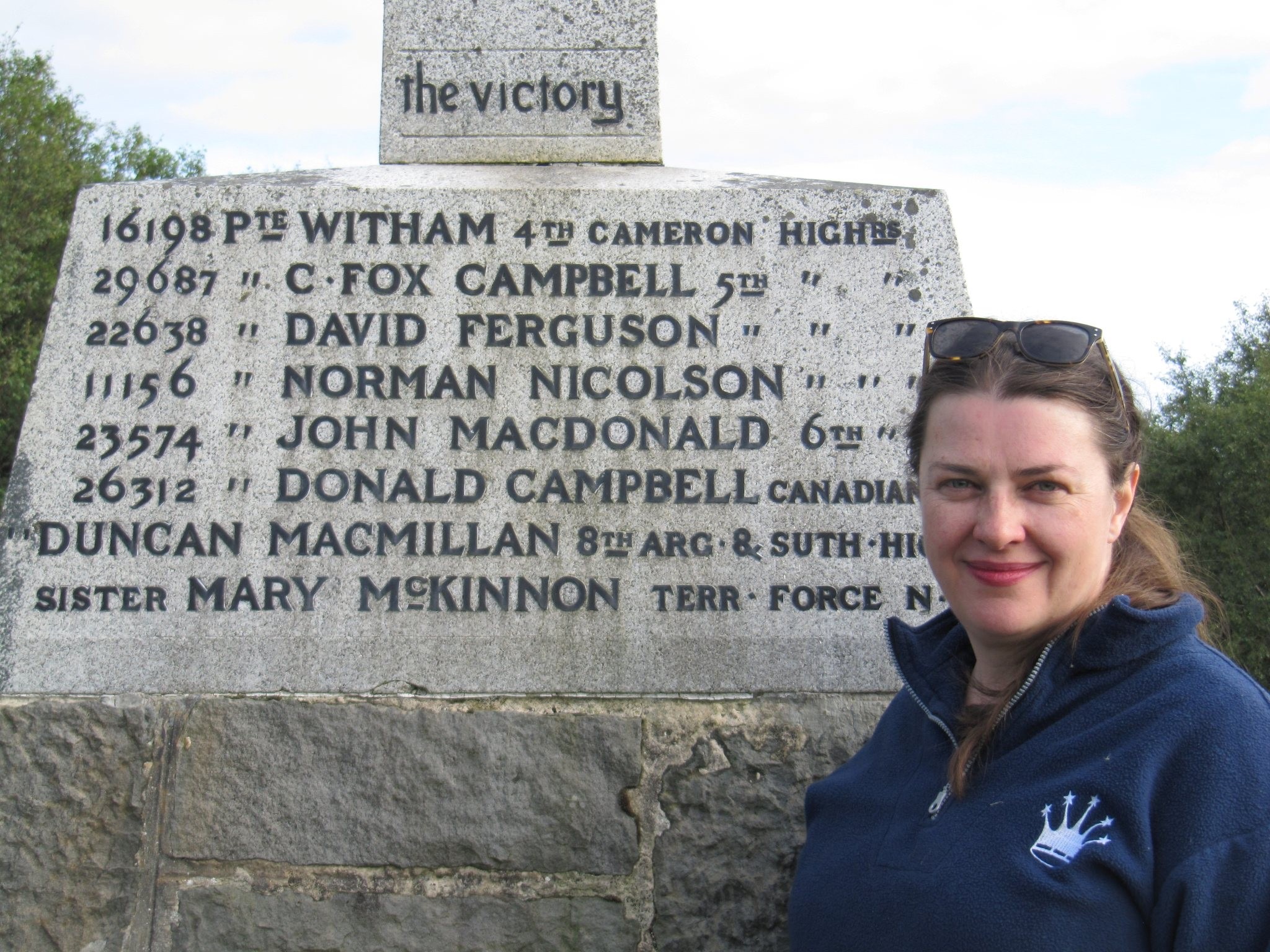 Woman standing in front of a stone plaque and looking at the camera 