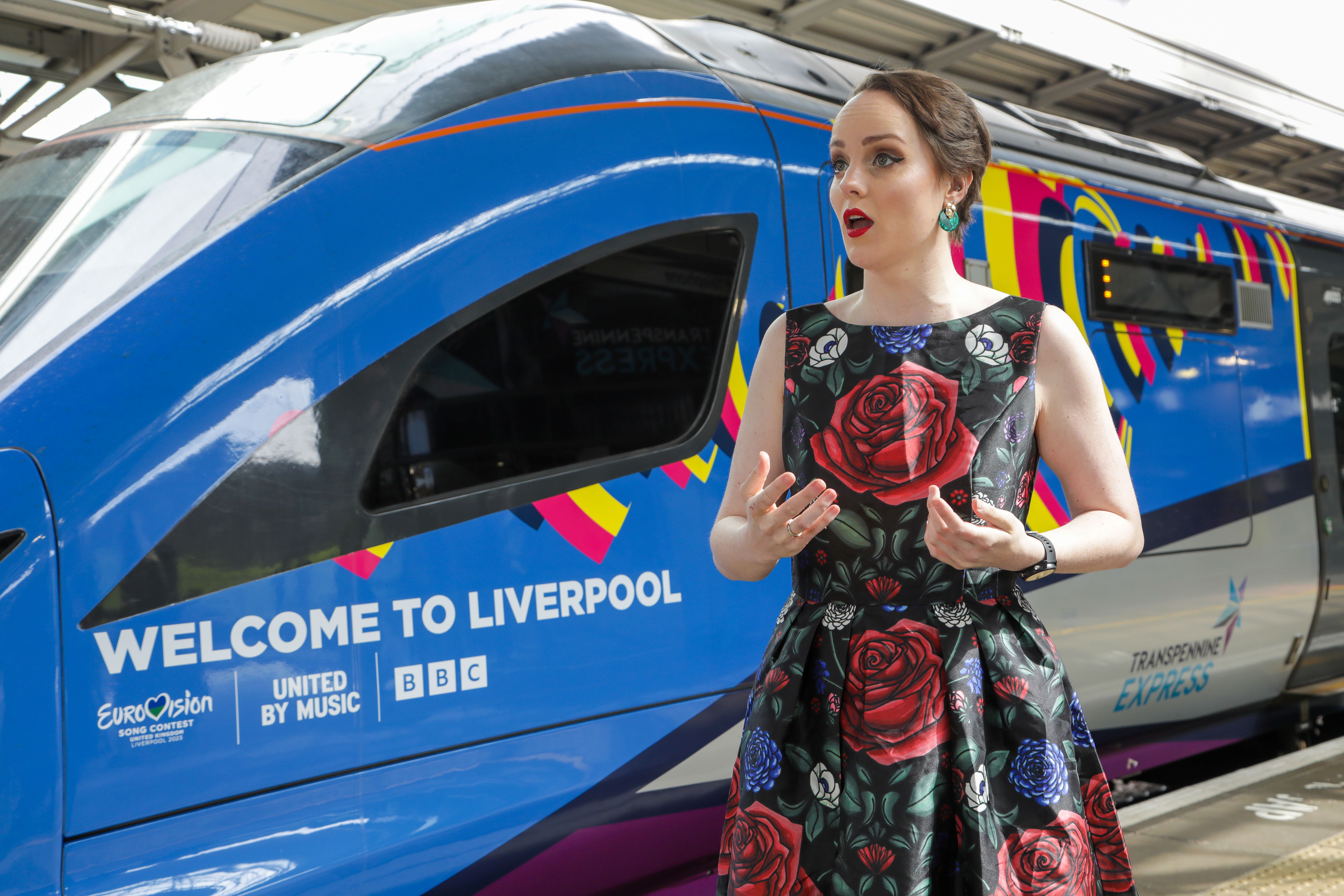 Morgan Carter singing in front of a train displaying Eurovision livery
