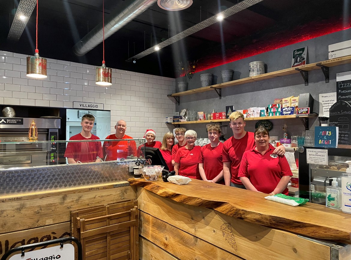 Gerry Sweeney (second from left) pictured with his employees stood inside and behind the counter of Villaggio Pizza, Scotland