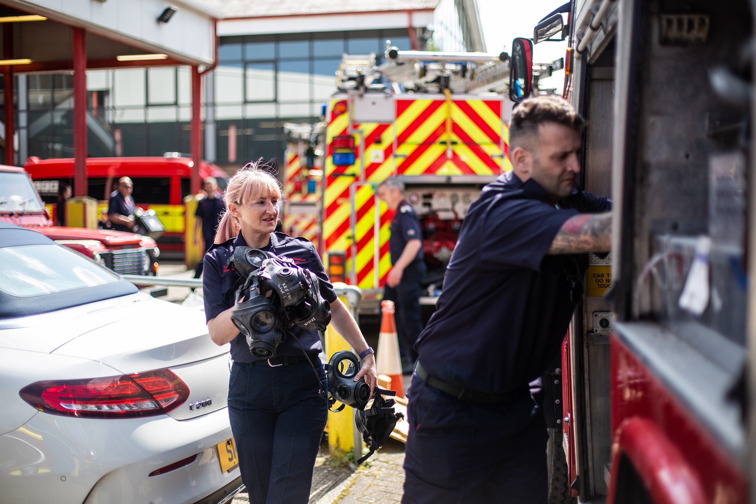 Two firefighters lifting equipment onto fire engines