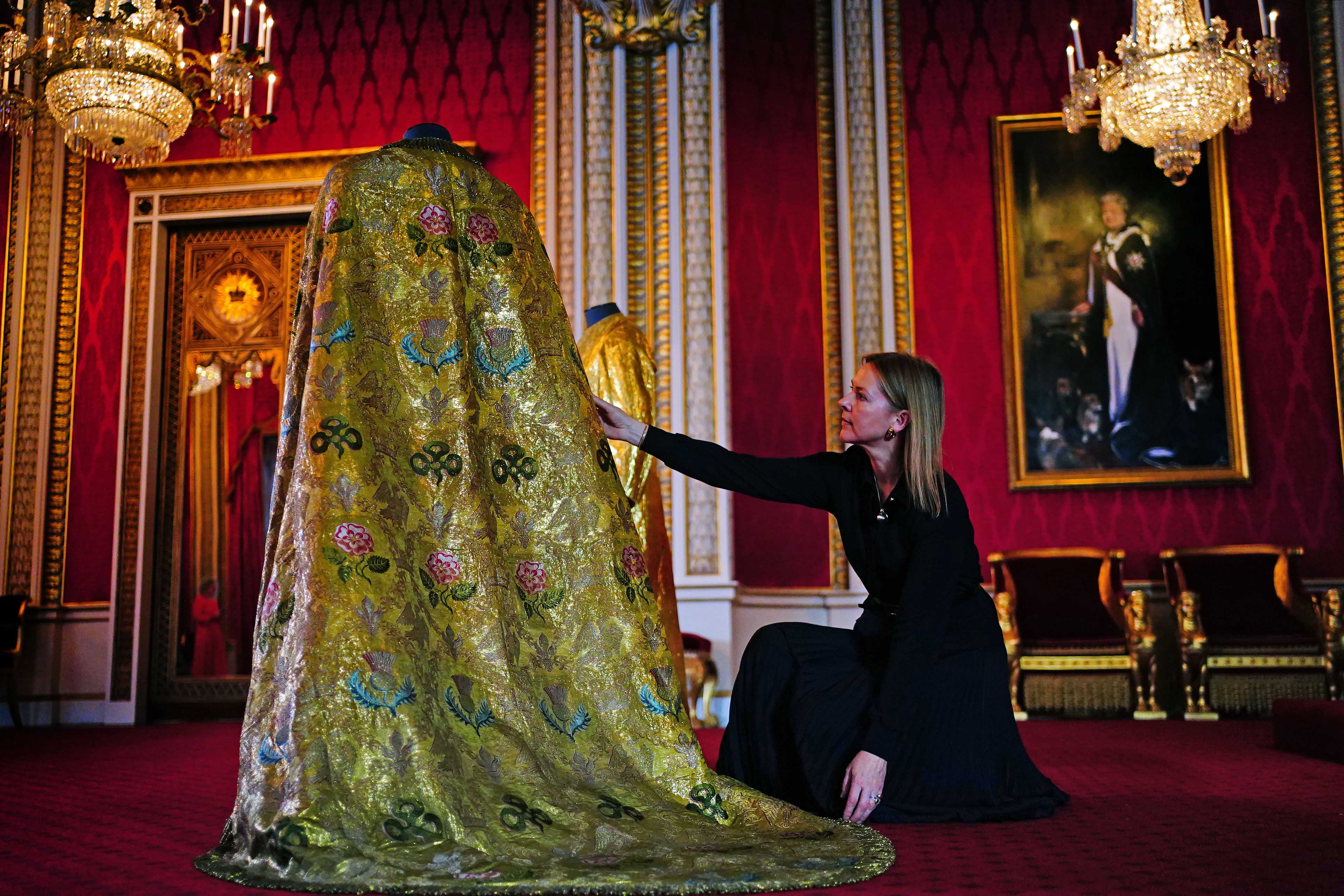 Caroline de Guitaut, deputy surveyor of the King's Works of Art for the Royal Collection Trust, adjusts the Imperial Mantle in the Throne Room at Buckingham Palace 