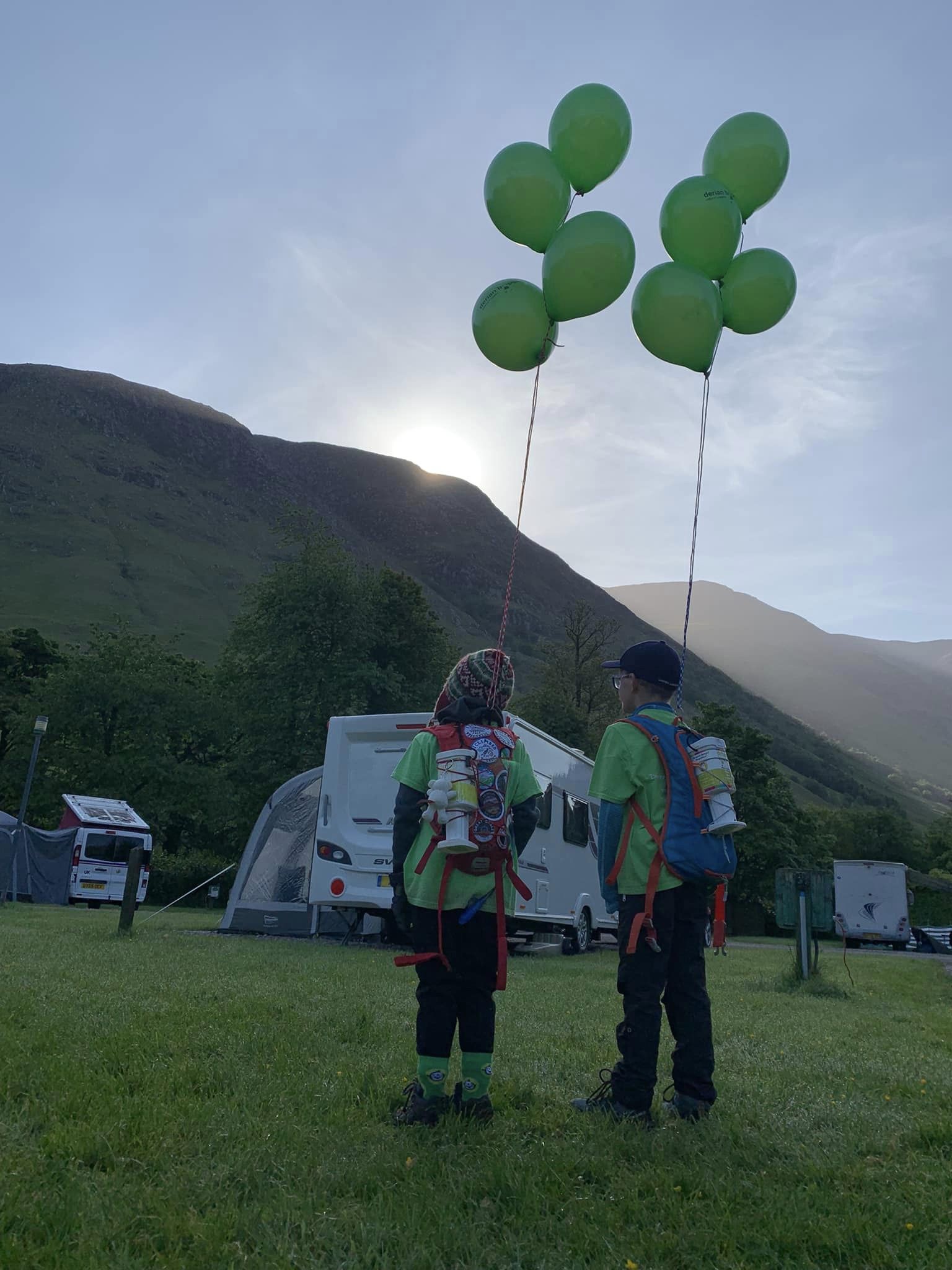 Two boys with balloons on them, looking into the sky