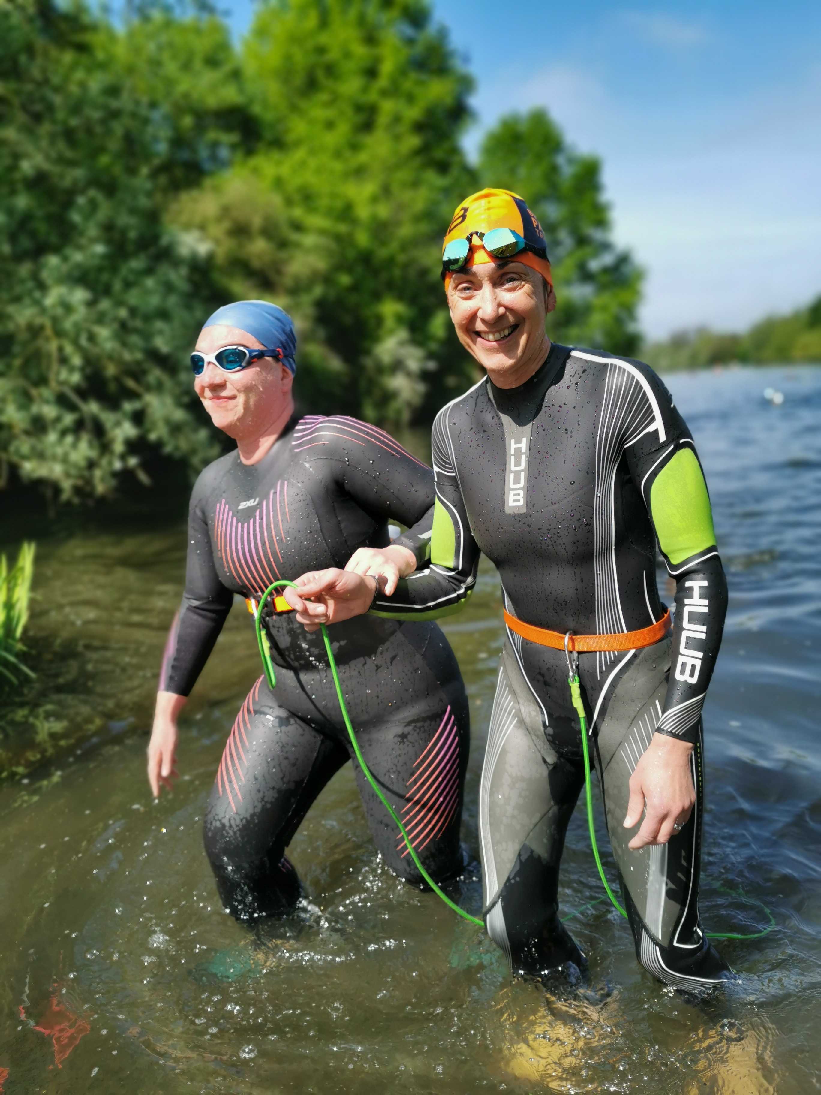 Tow women wearing wetsuits and swimming hats