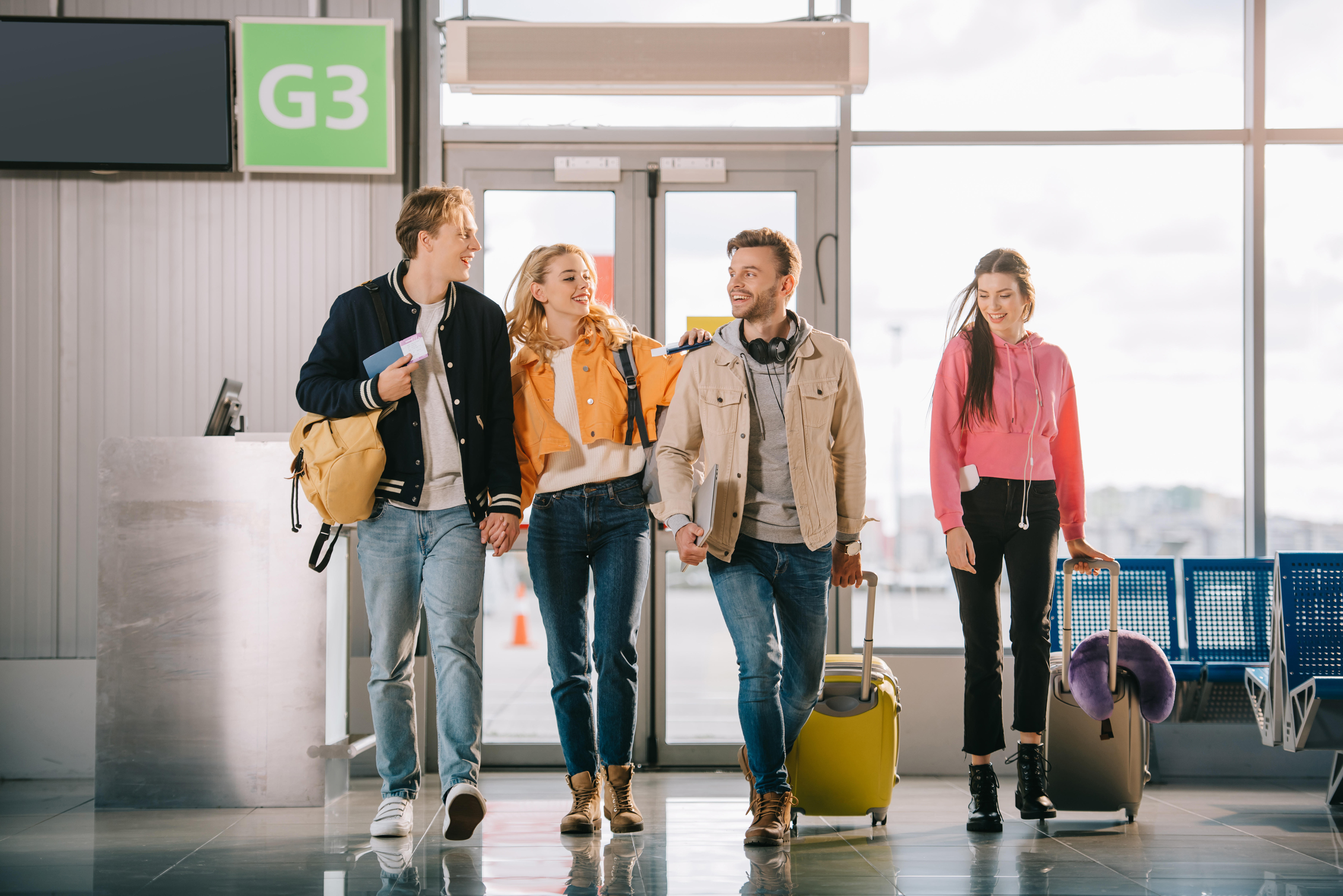 four friends at airport with luggage