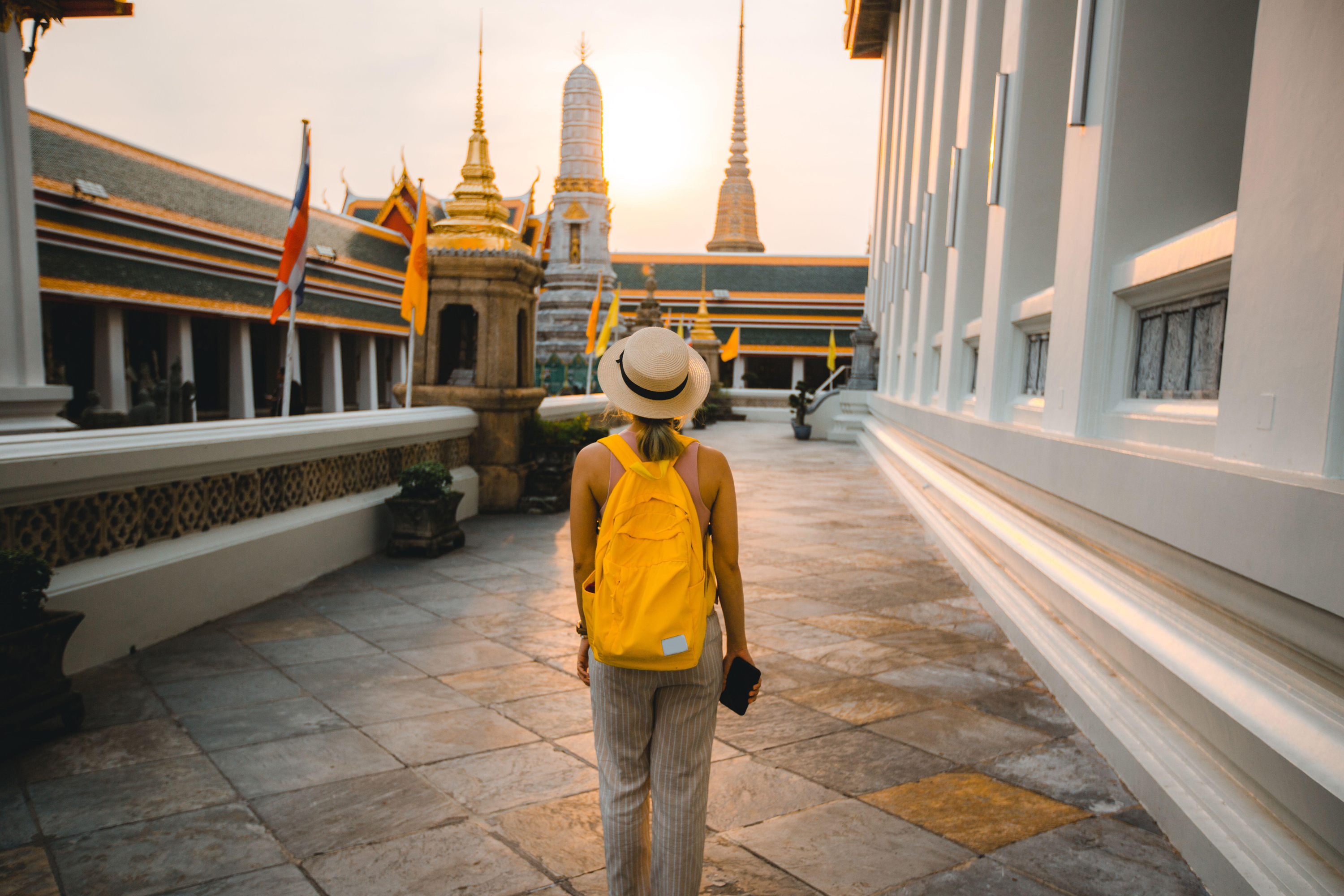 Woman with backpack and hat walking in Wat Pho at Bangkok
