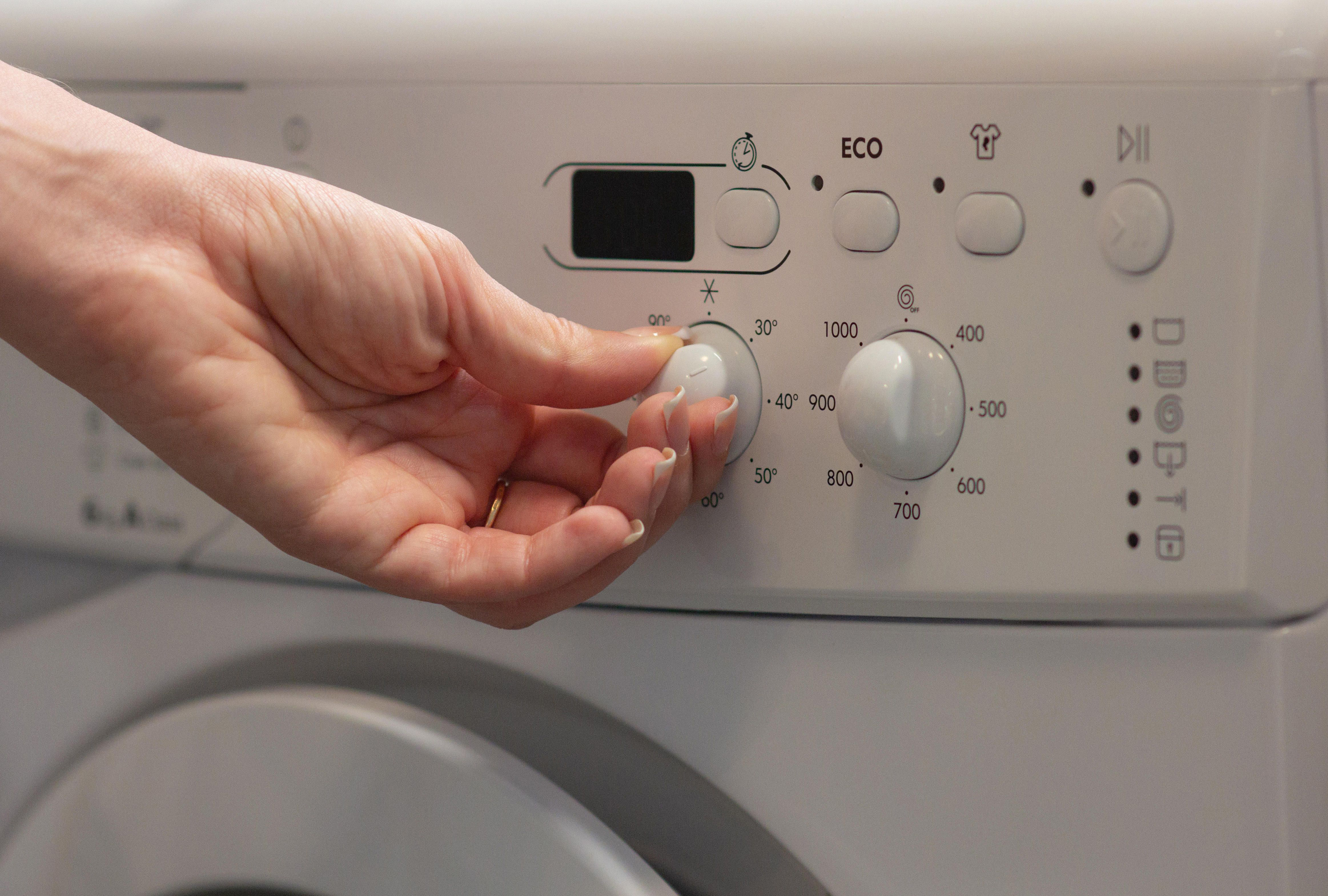 Woman switching temperature on eco friendly washing machine