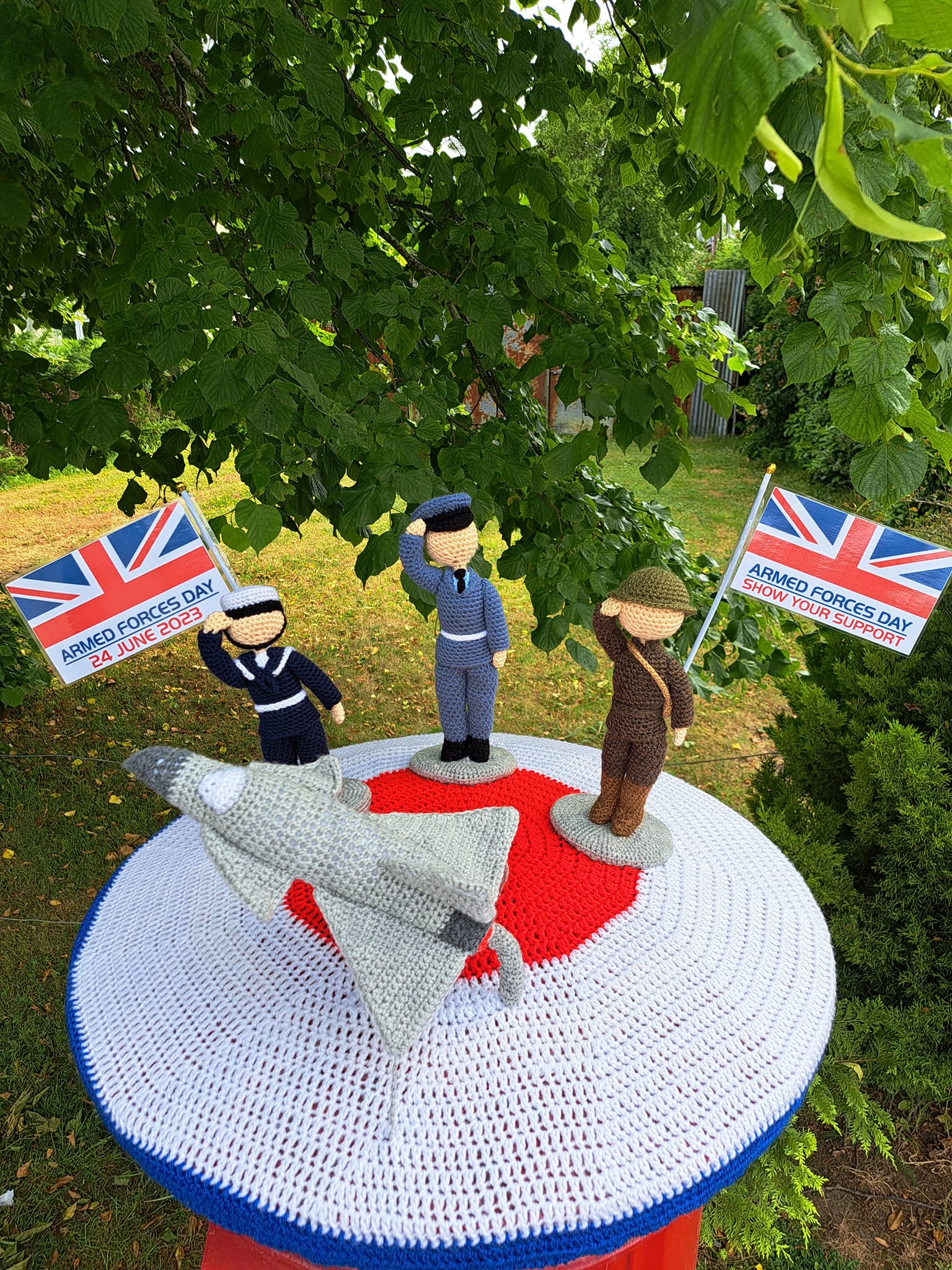 Crocheted people and an aircraft on top of a postbox