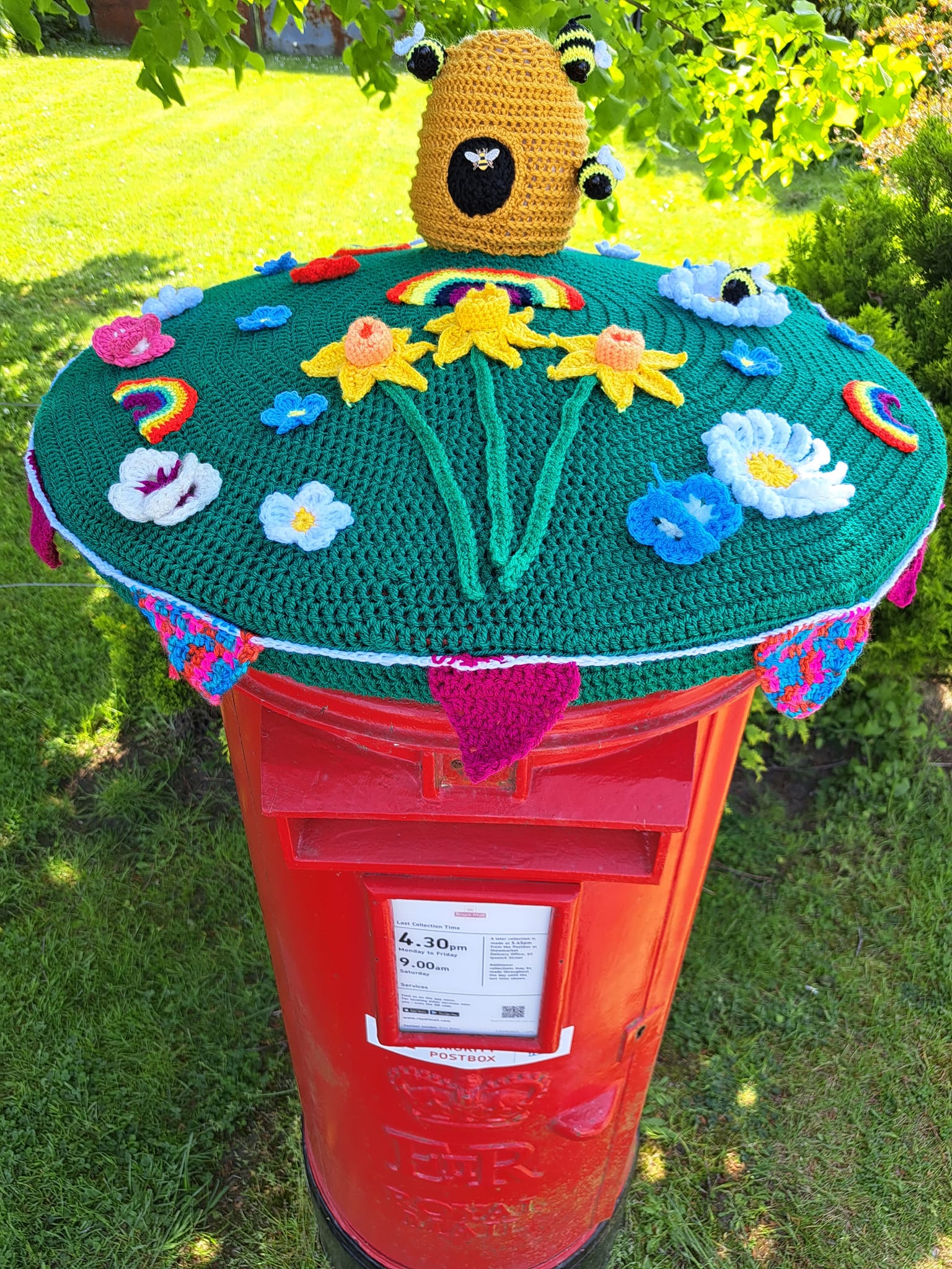 Crocheted flowers and bees on top of a postbox 