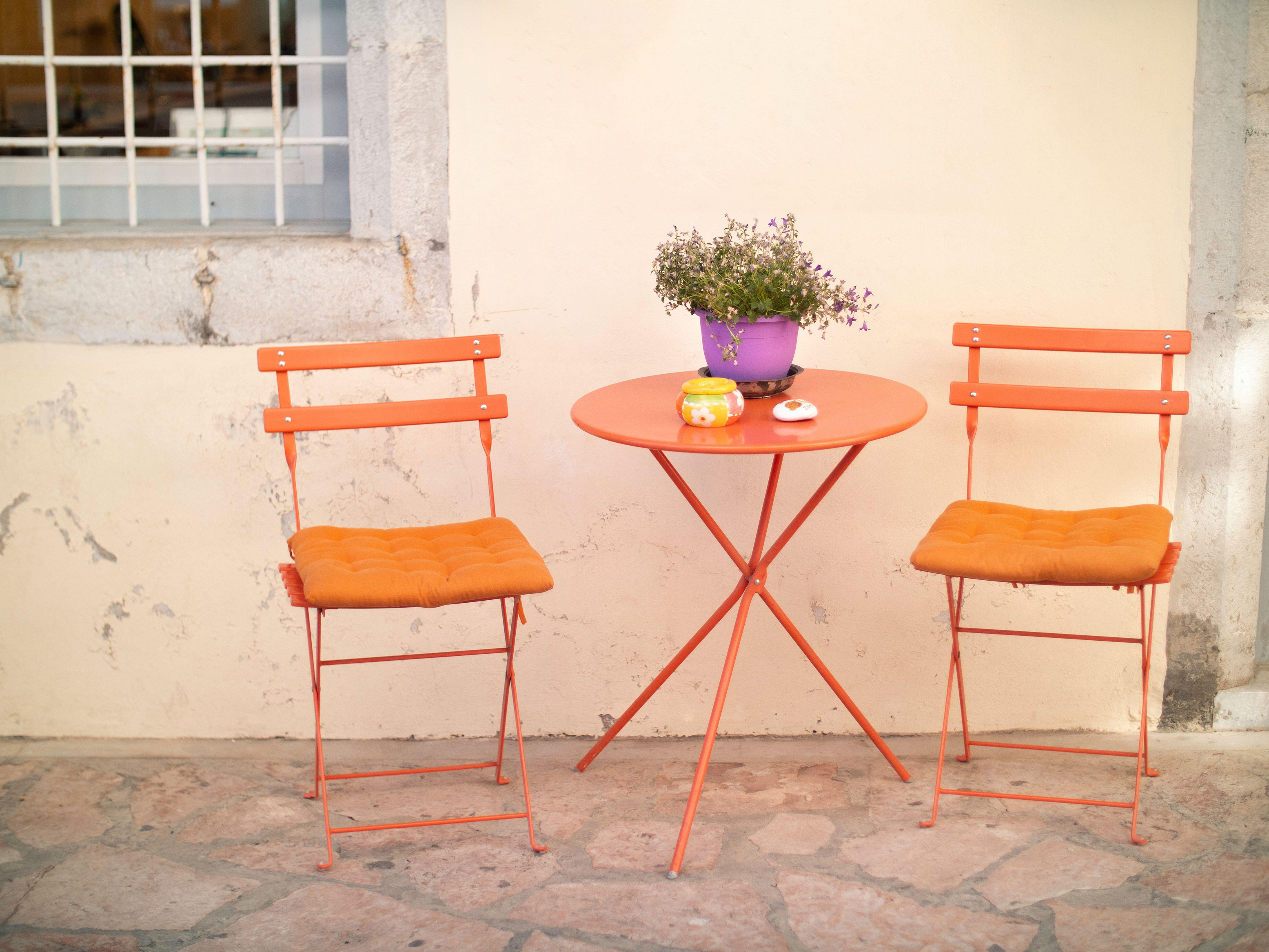 Orange metal outdoor chairs and table (Alamy/PA)
