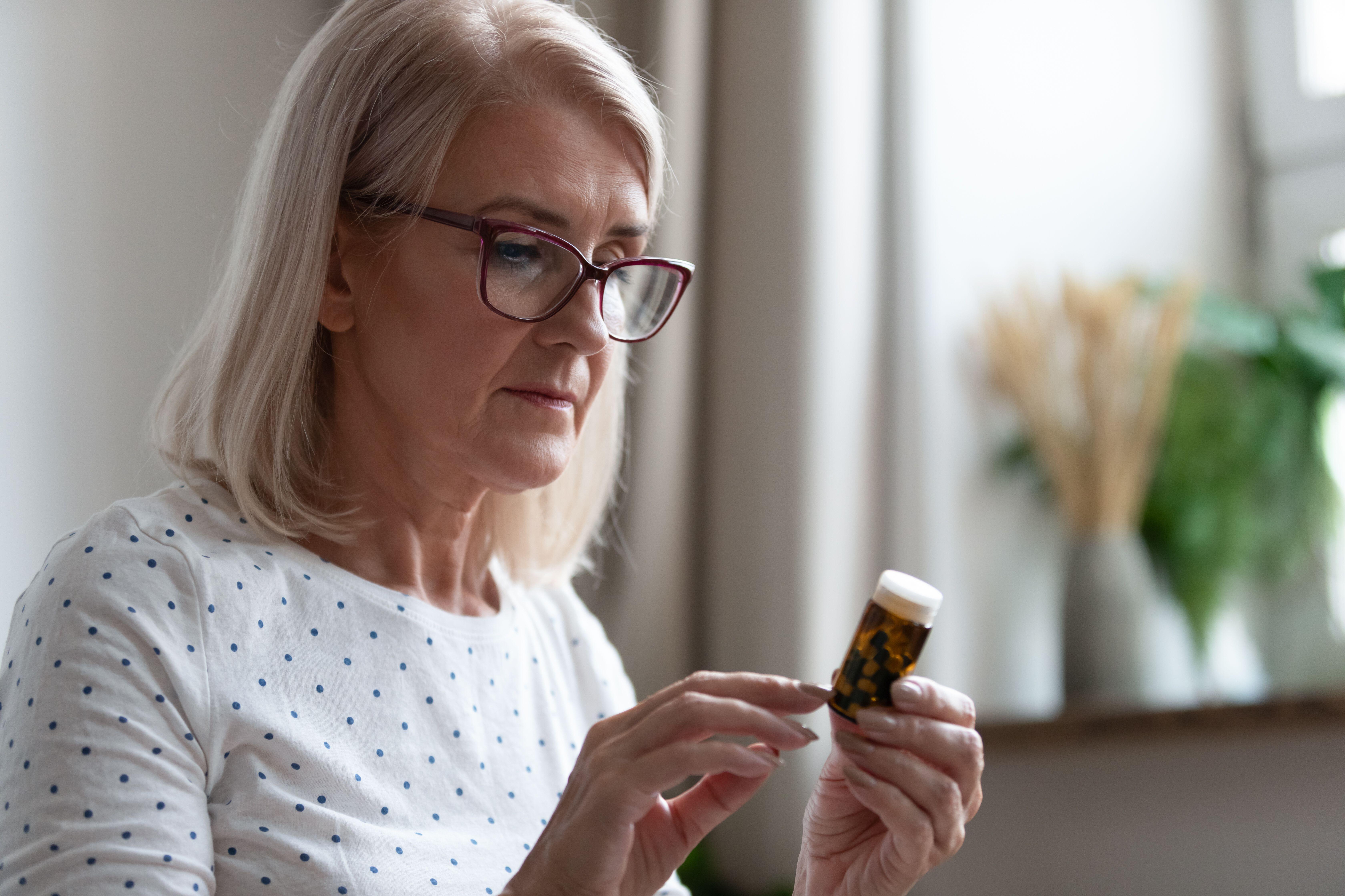 A woman reading the label on a pill bottle