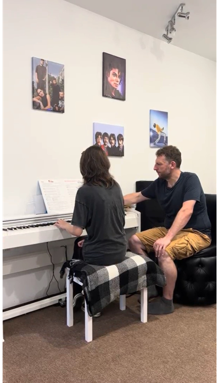 Man sitting next to girl playing the piano