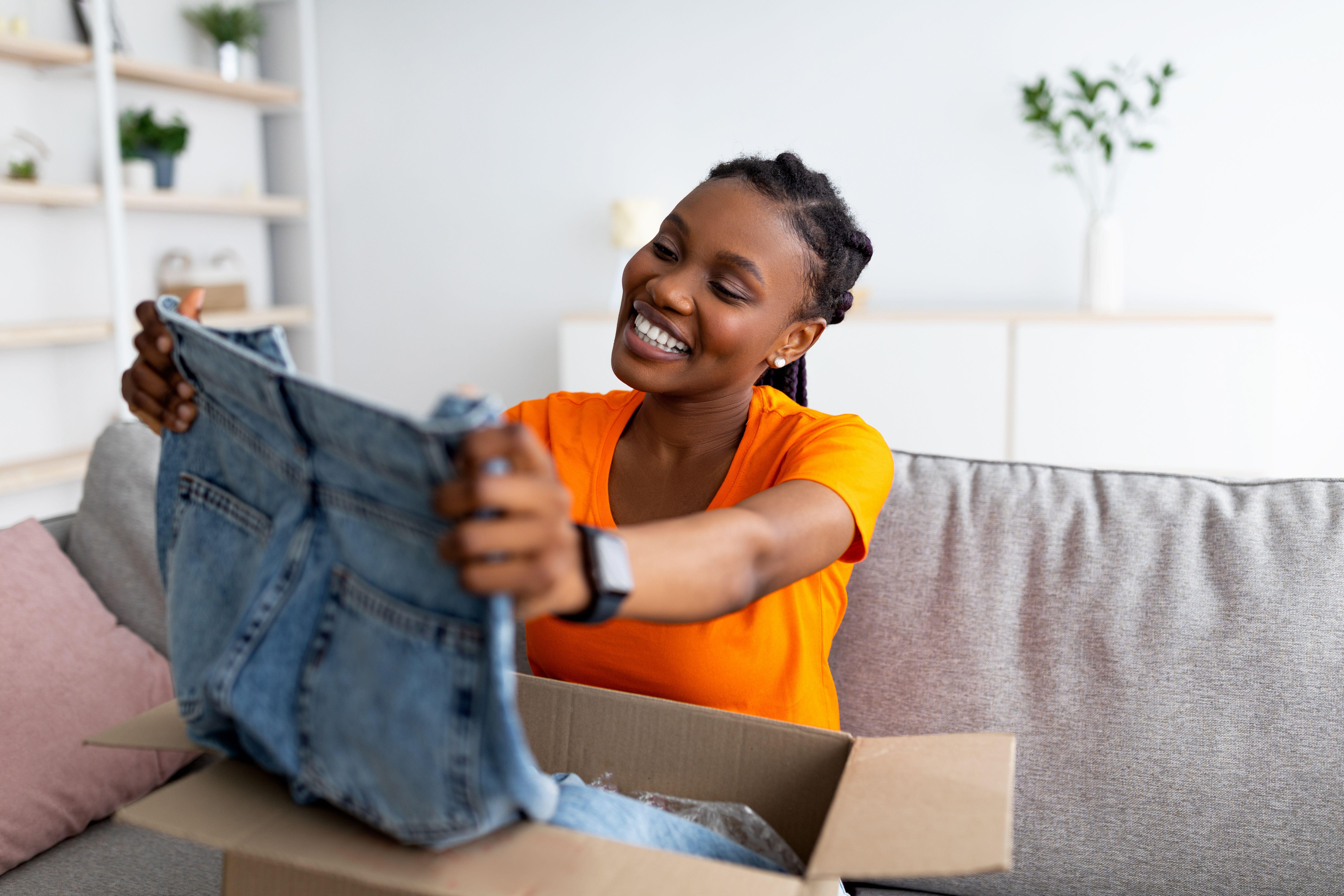 woman opening jeans from online shopping at home