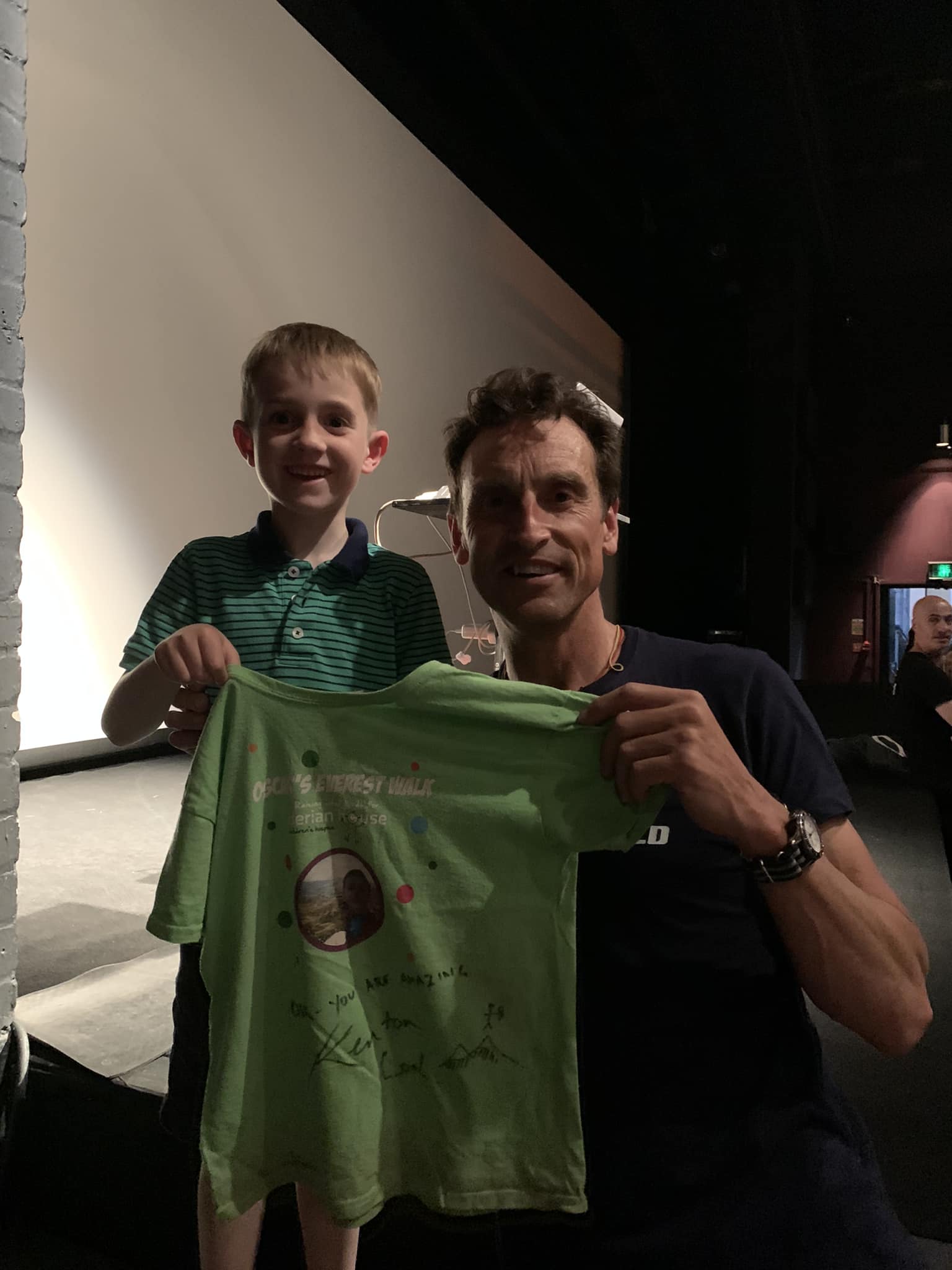 Boy and man holding a T-shirt and smiling at the camera 