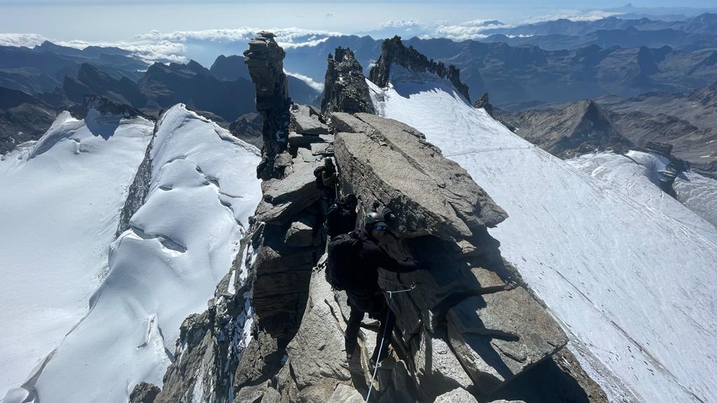 The trio scaling a rock face during their climb surrounded by snow
