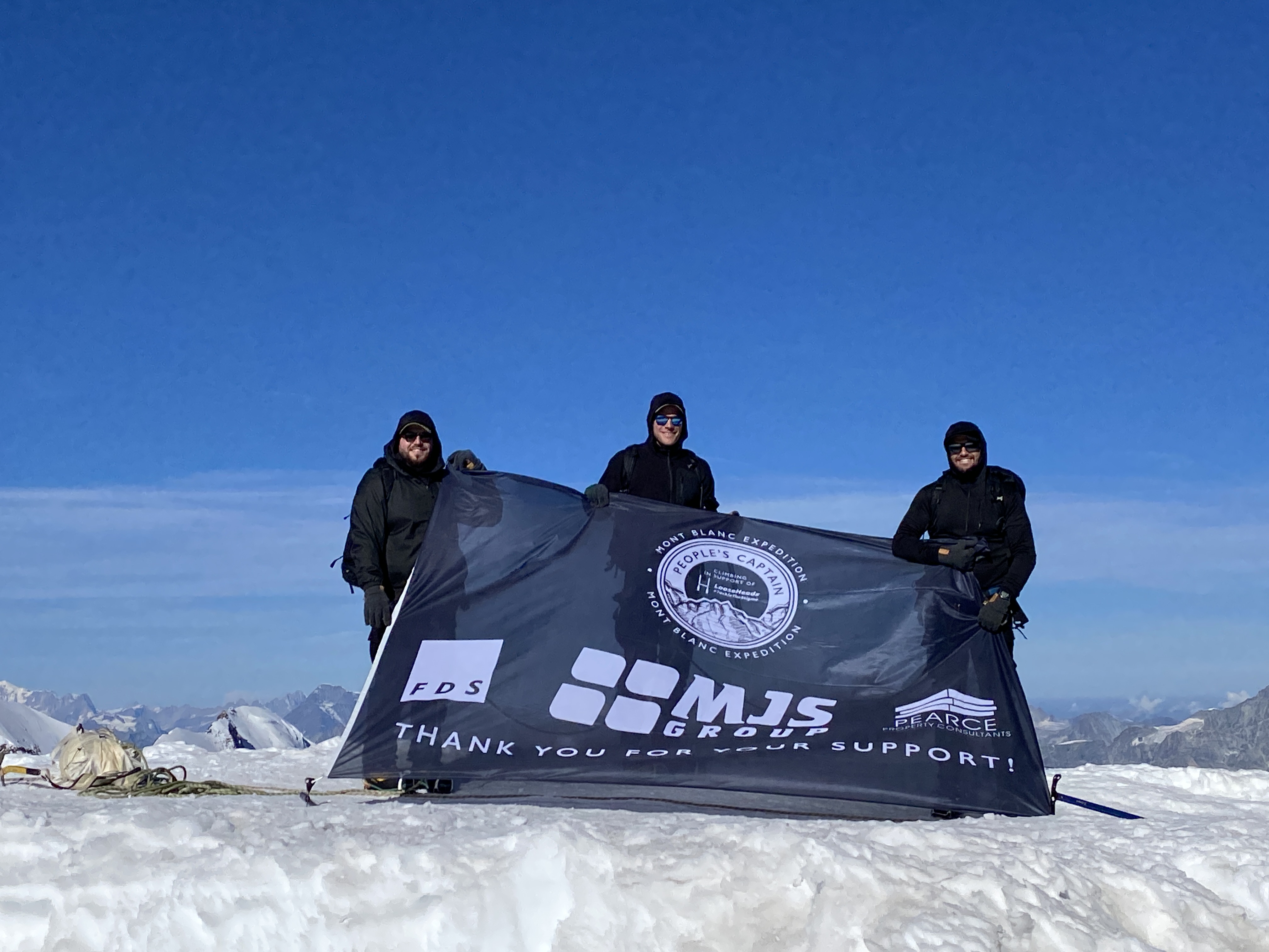 The trio at the summit of Monte Rosa, holding a banner 