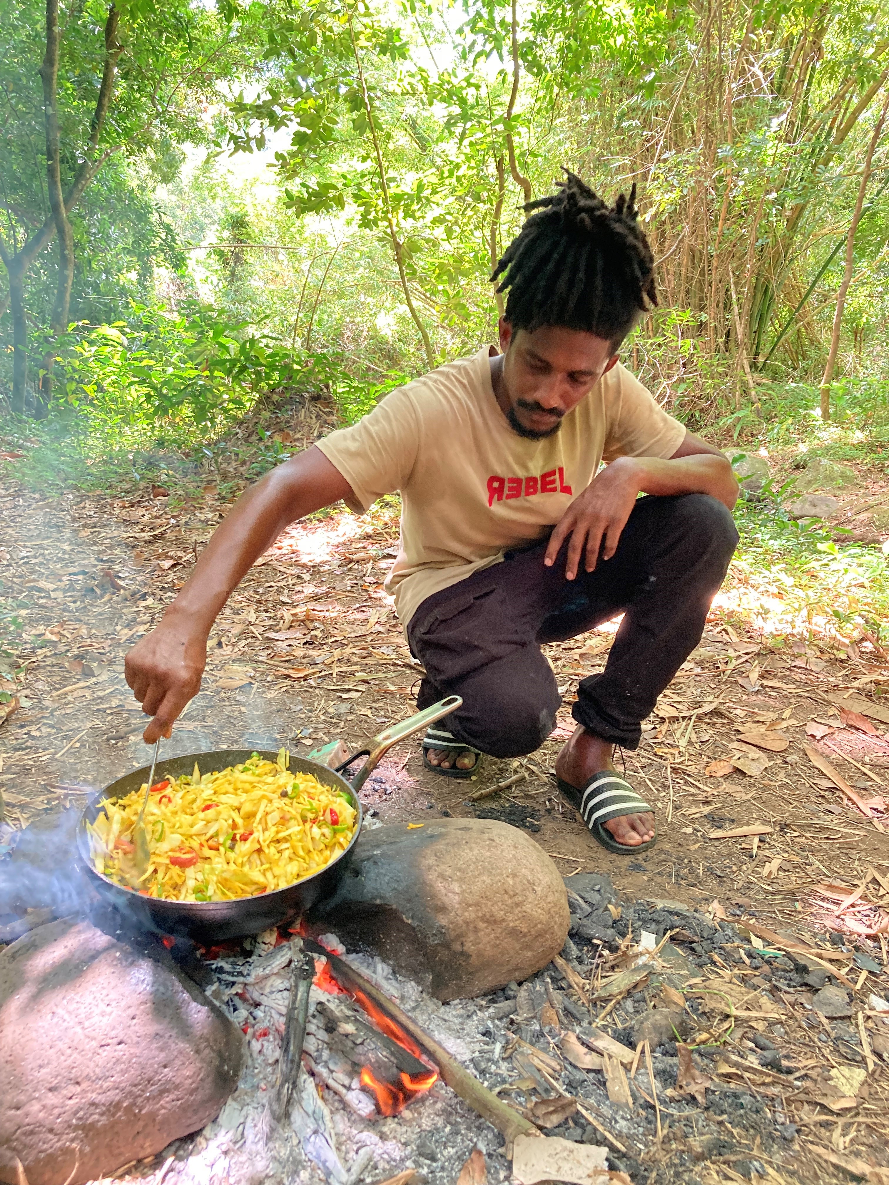 Joachim Joseph cooks a vegan meal aside Annandale Waterfall, Grenada (Hannah Stephenson/PA)