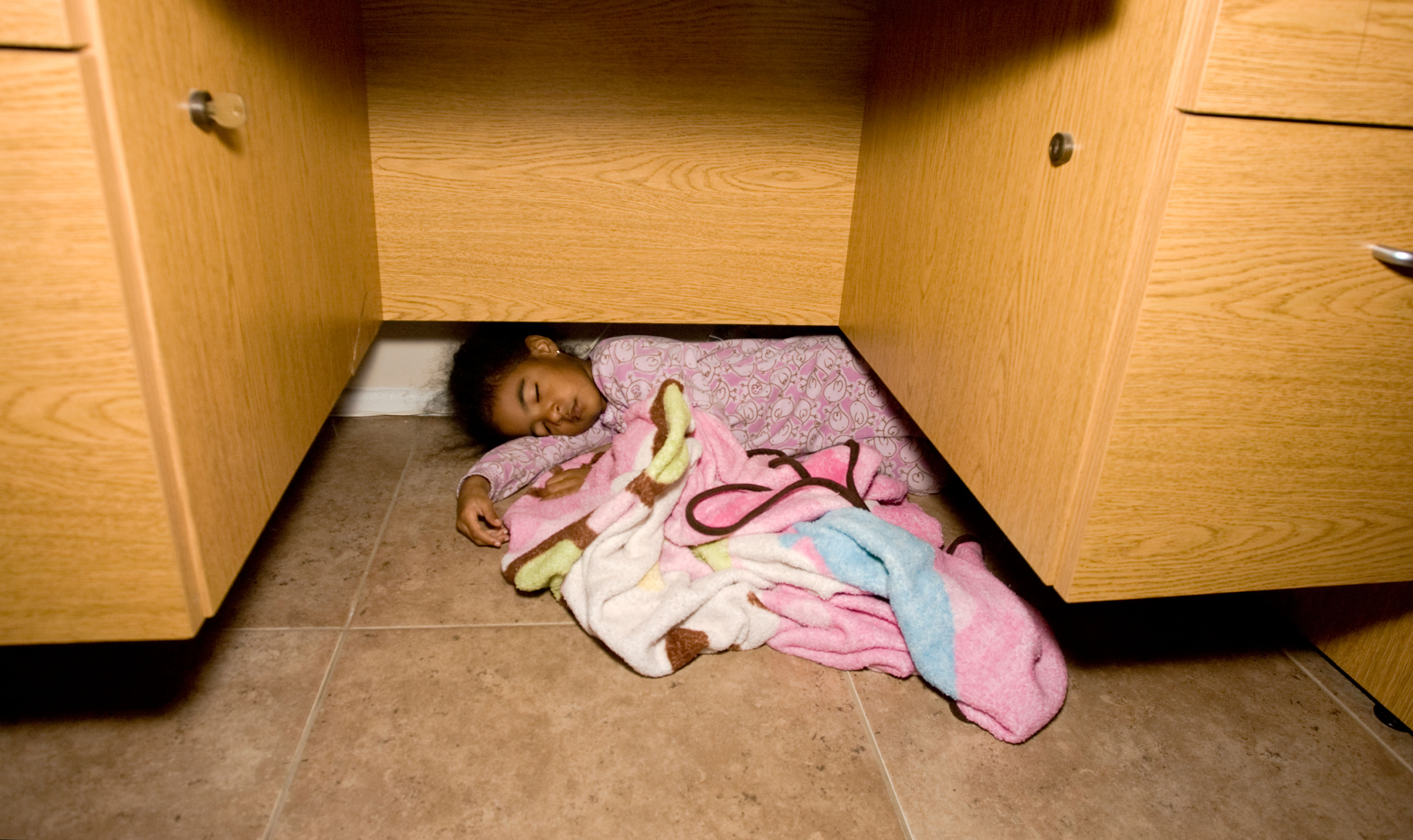 Child sleeping on the floor under a desk