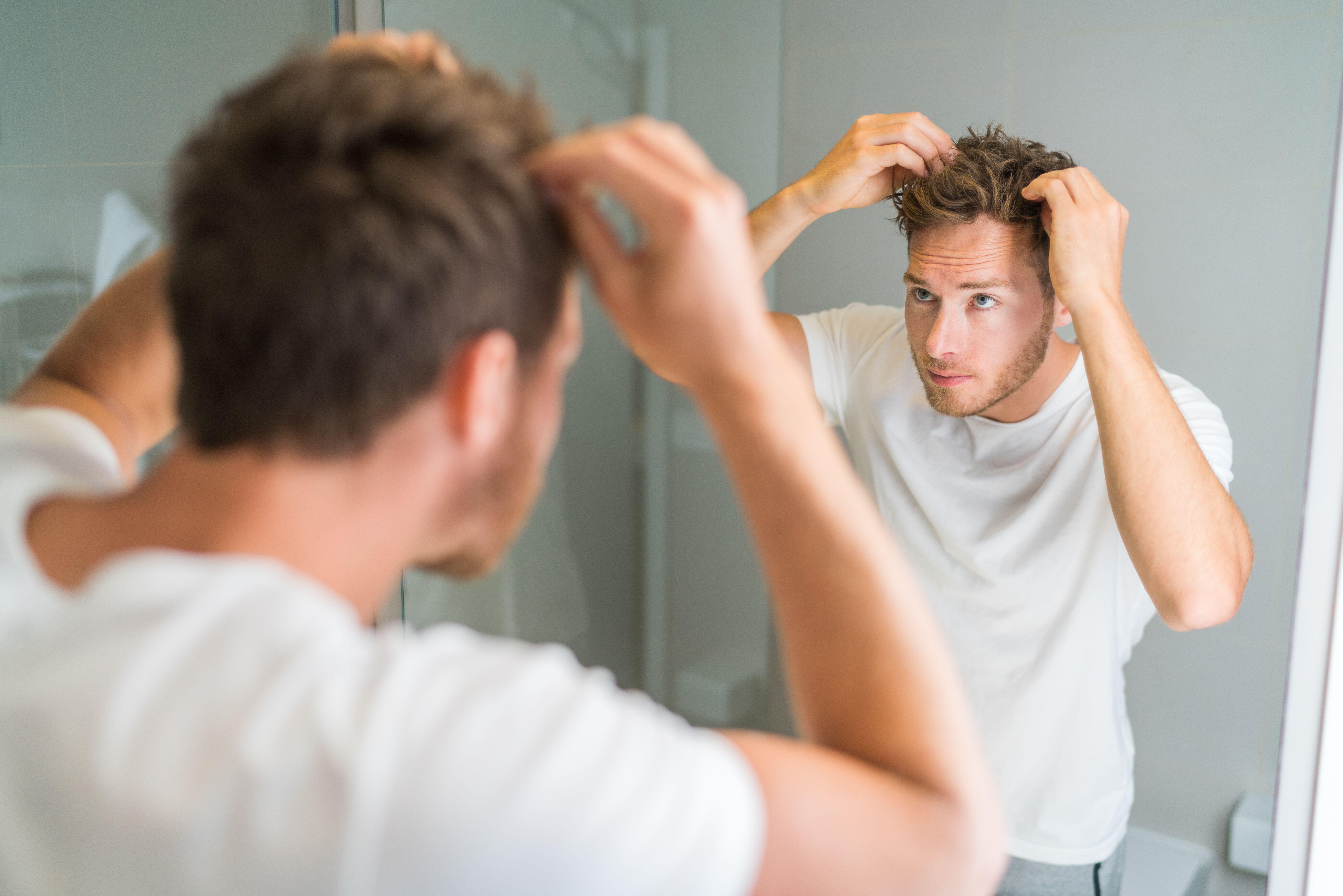 man looking at scalp in mirror