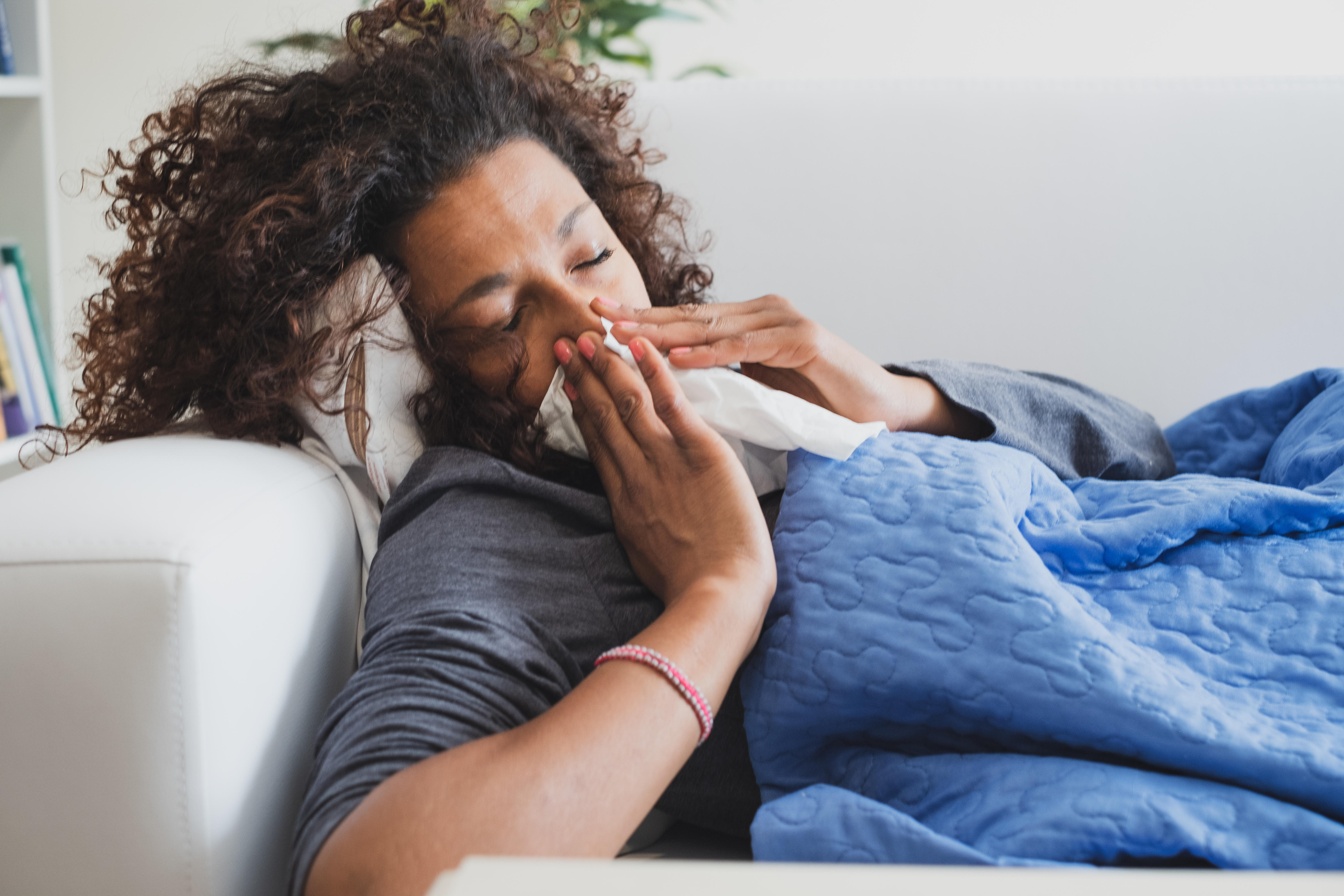 Sick black woman at home blowing her nose