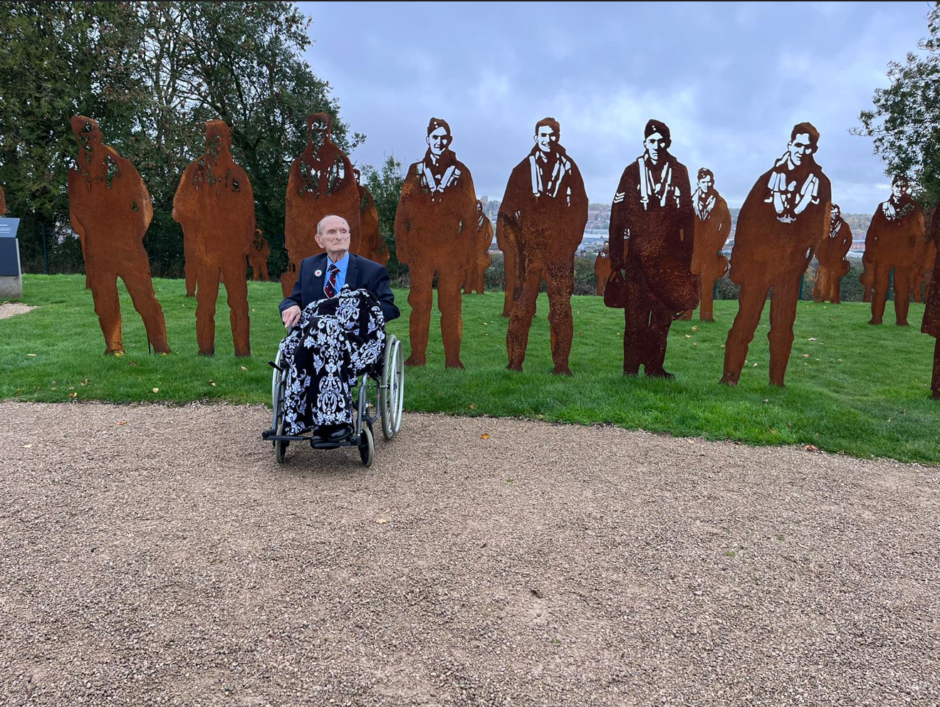 WWII veteran sat in wheelchair next to memorial statues